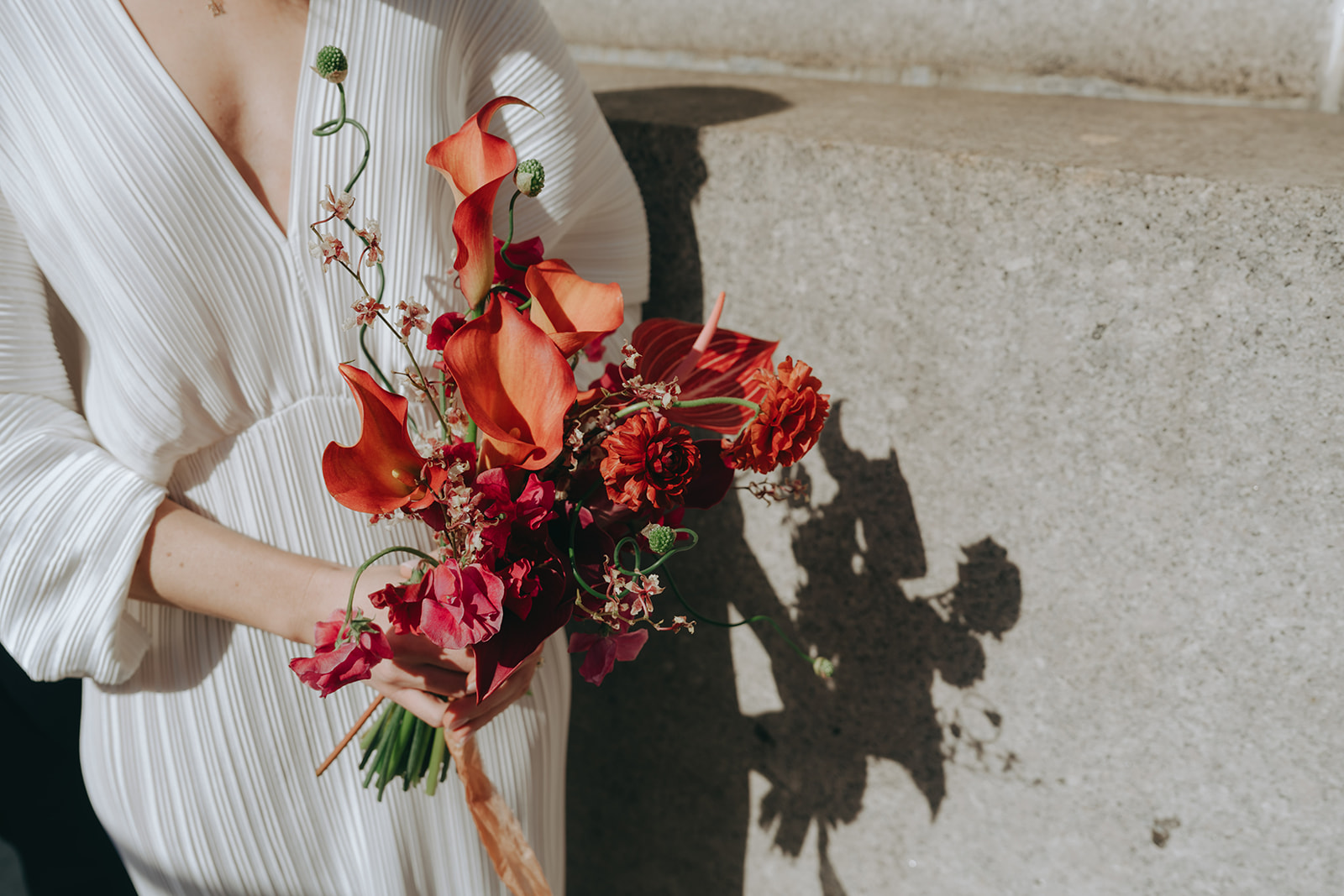 Rachel and Dave’s 2 day celebration Close up of the bride, in her white dress, holding her colorful bouquet by NYC city hall wedding photographer Elsie Goodman.
