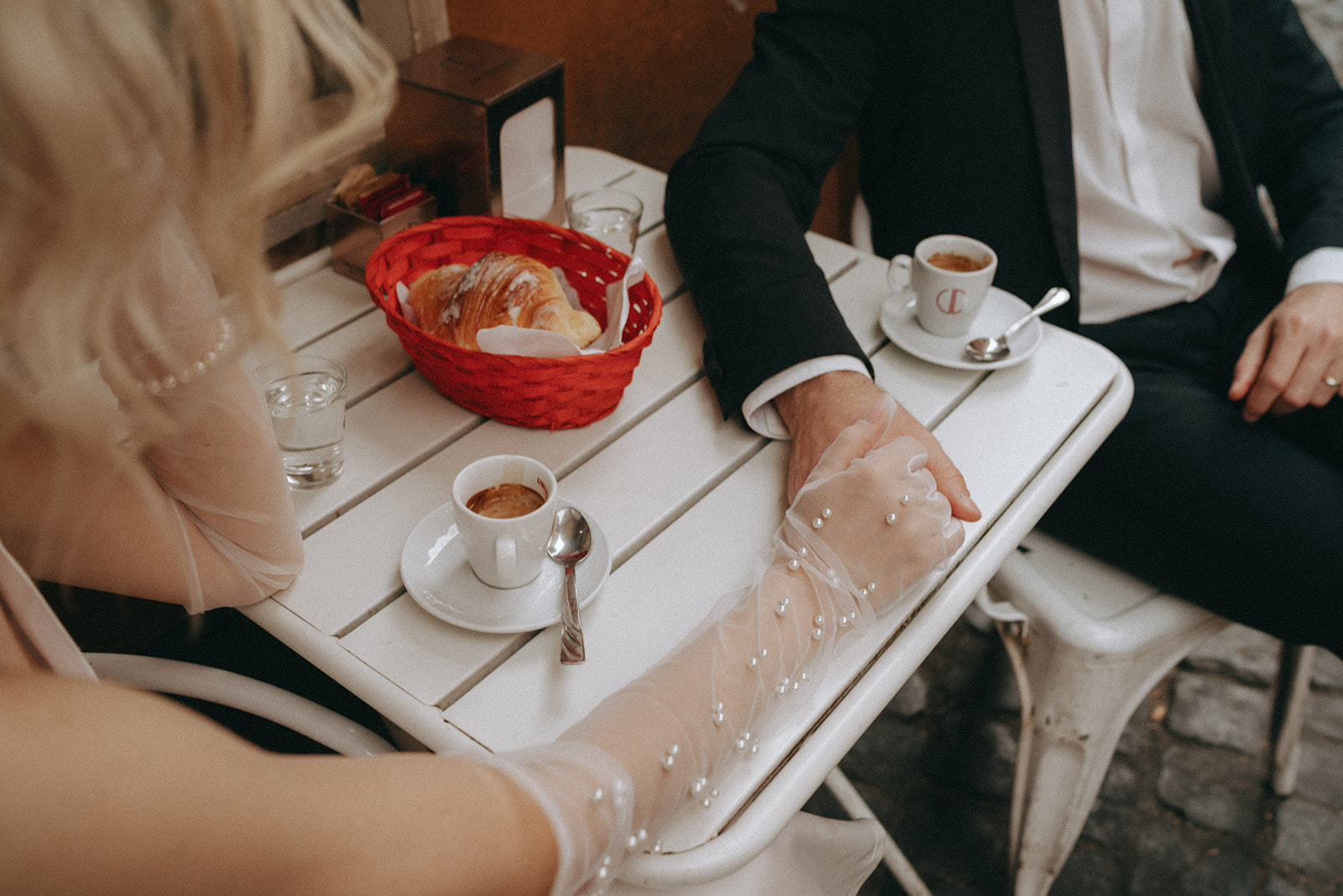 Bride and groom hold hands across a small Trastevere coffee shop table after exchanging vows by Rome elopement photographer Elsie Goodman.