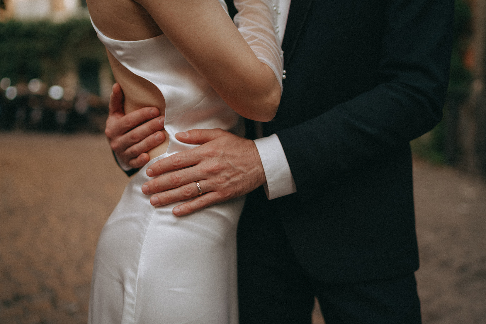 Close up of a grooms wedding ring, he has his arms wrapped around her waist by Rome elopement photographer Elsie Goodman.