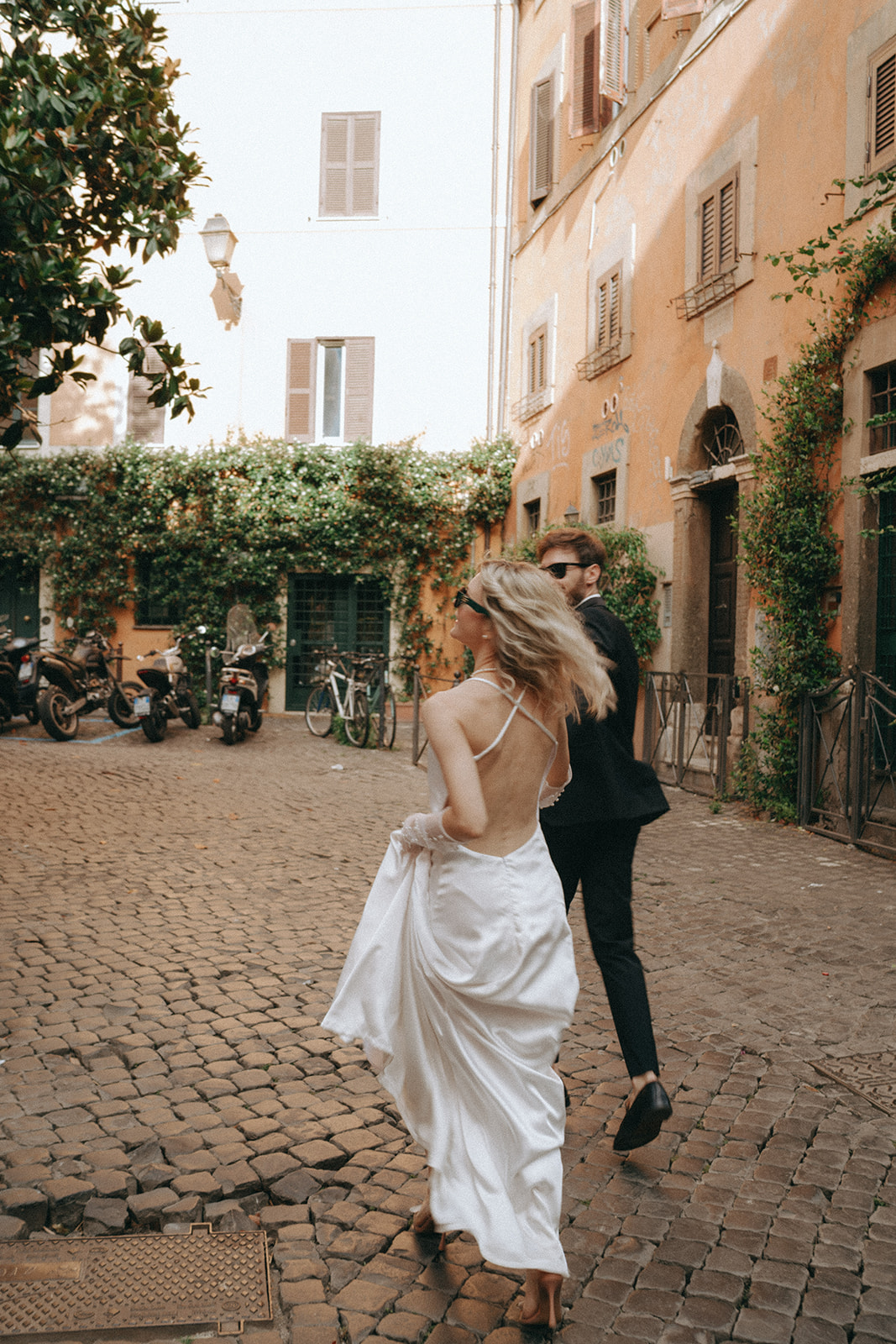Bride and groom walking down cobblestone streets by Rome elopement photographer Elsie Goodman.