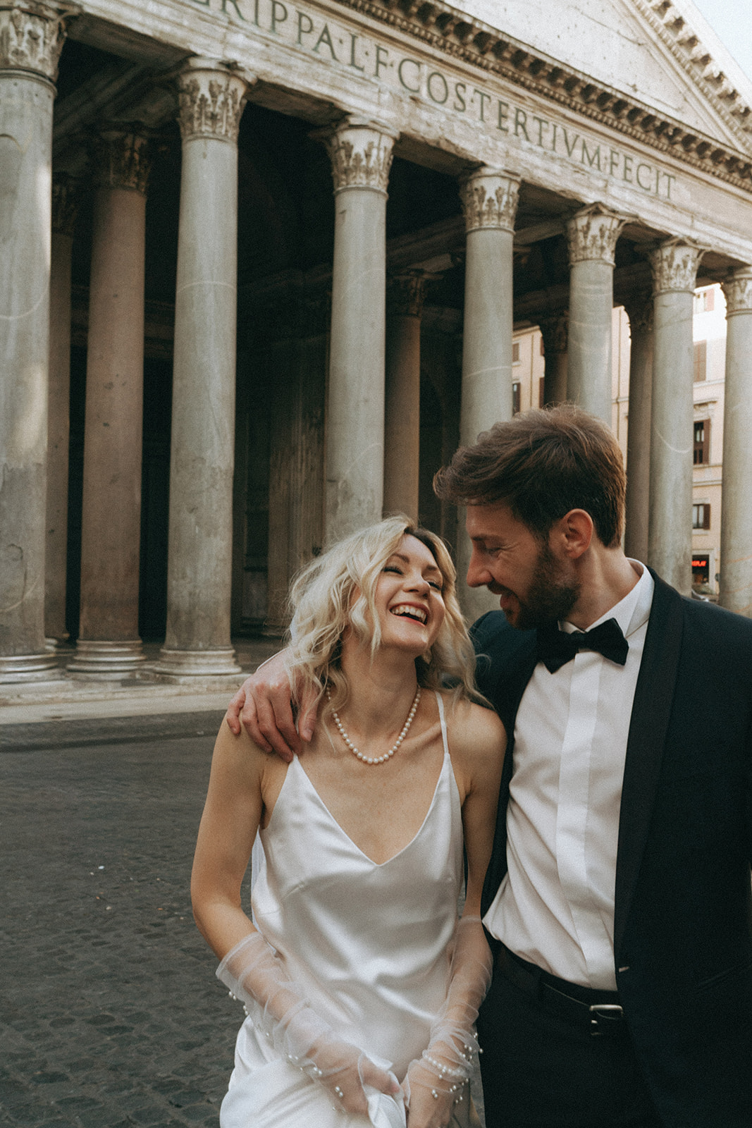 Bride and groom looking at each other in pure bliss, smiling in the background the Pantheon in the morning light by Italy elopement photographer Elsie Goodman.