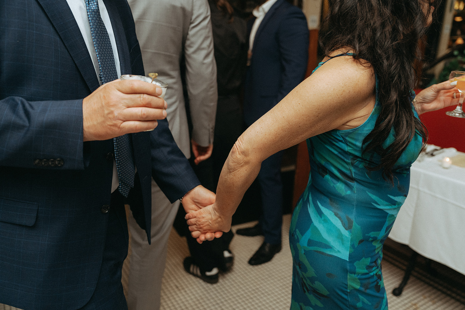 Madison + Dylan 620 Loft and Garden Wedding detail shot of woman leading man by the hand at wedding reception, shot by elsie goodman, a destination and NYC wedding photographer