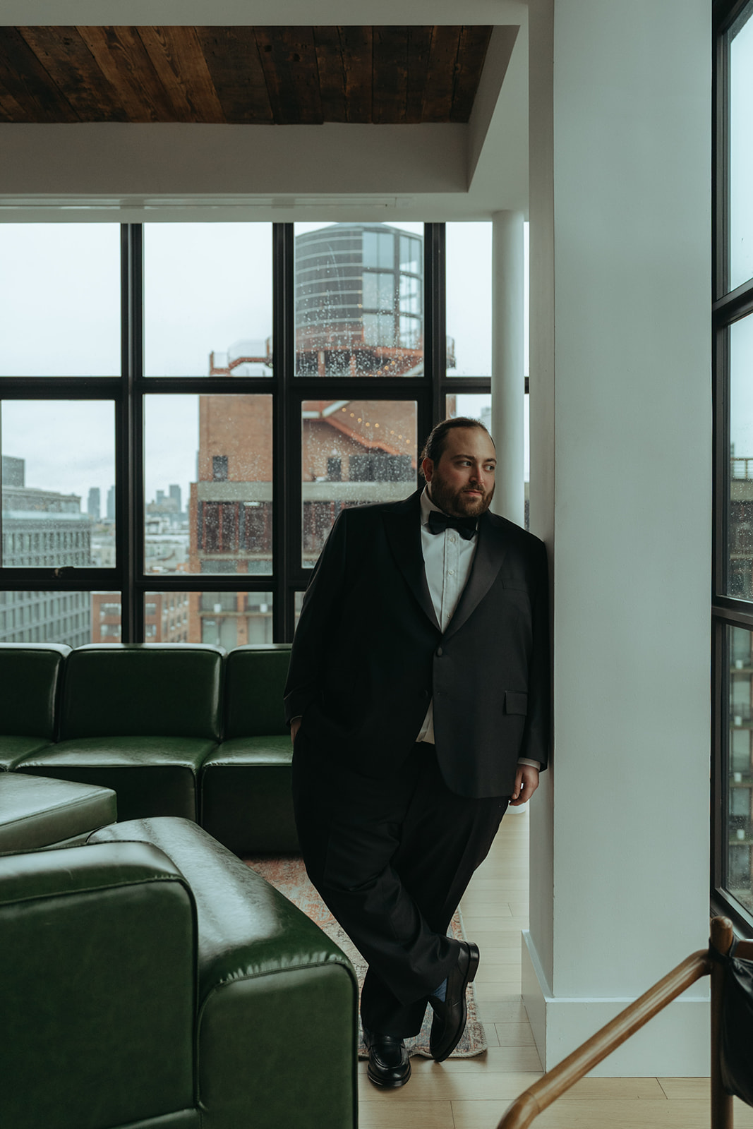 Madison + Dylan's 620 Loft and Garden Wedding groom looking out window at wythe hotel in nyc, shot by elsie goodman, a destination and NYC wedding photographer
