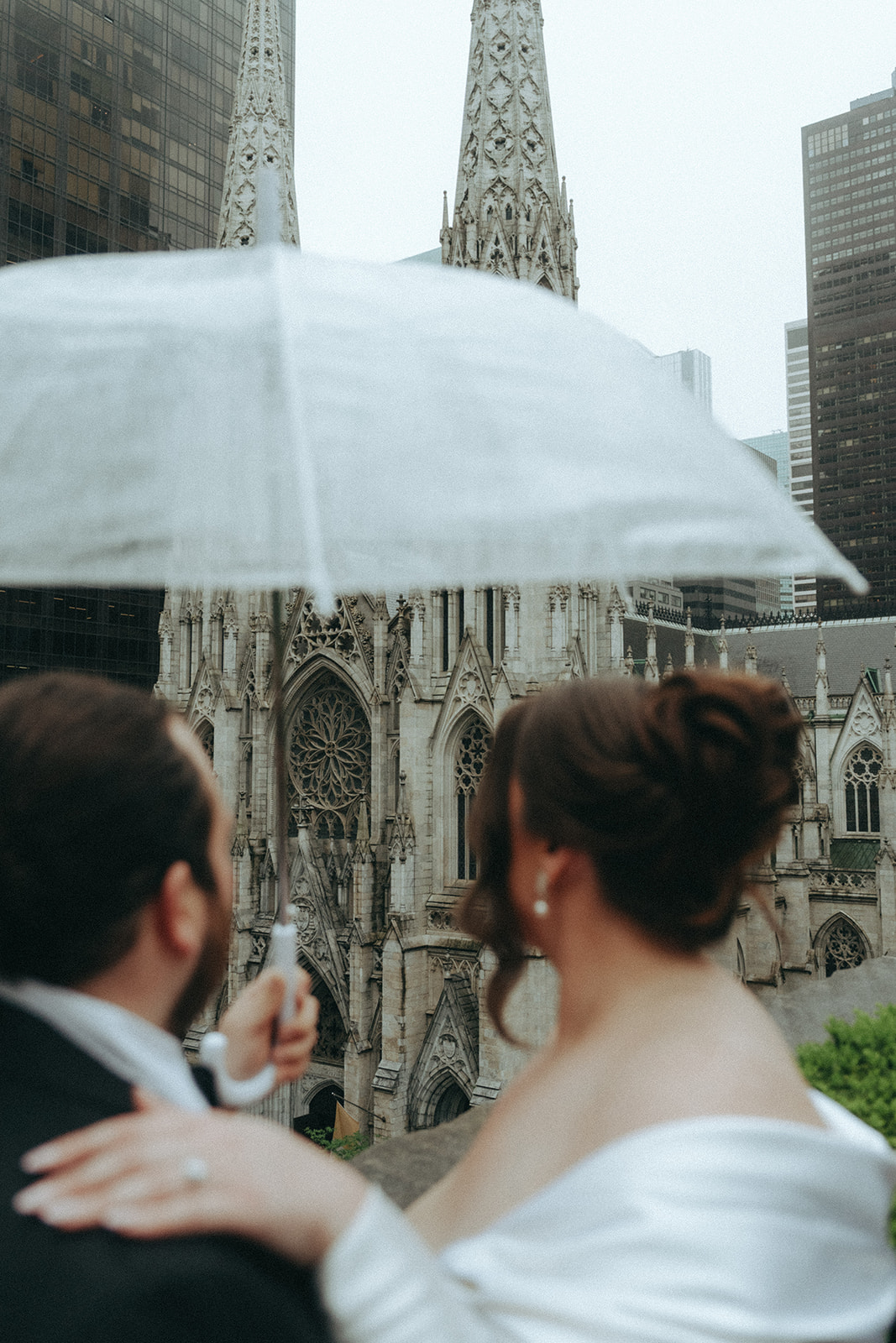 Madison + Dylan 620 Loft and Garden Wedding bride and groom under umbrella looking at cathedral at 620 loft & garden wedding, shot by elsie goodman, a destination and NYC wedding photographer