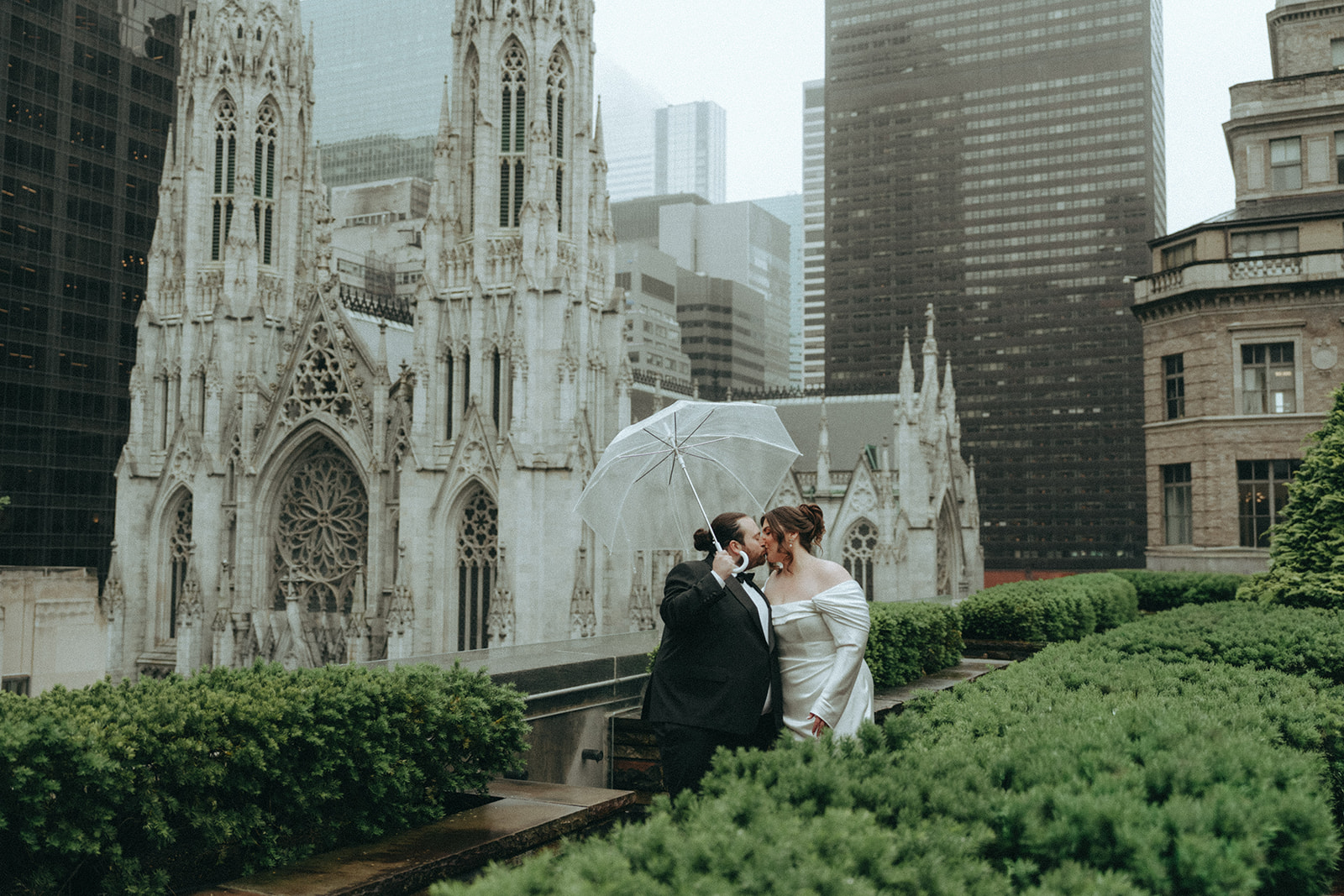 Madison + Dylan 620 Loft and Garden Wedding bride and groom kissing on rooftop with umbrella at 620 loft & garden wedding, shot by elsie goodman, a destination and NYC wedding photographer