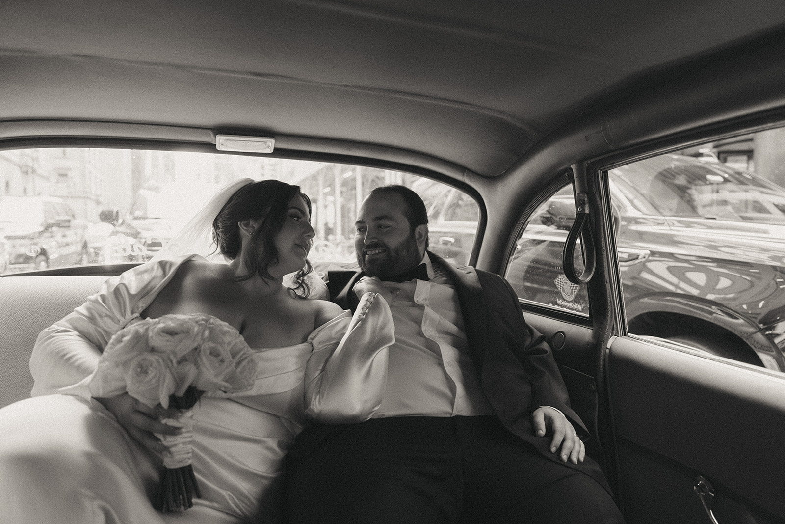 Madison + Dylan 620 Loft and Garden Wedding bride and groom riding in backseat of vintage taxi after 620 loft & garden wedding, shot by elsie goodman, a destination and NYC wedding photographer