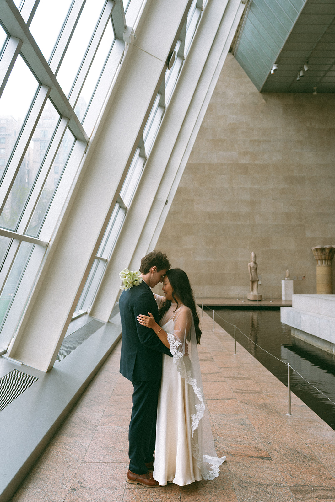 Alex + Bardo NYC Elopement Photos bride and groom holding each other next to windows at the Met for elopement photos, shot by elsie goodman, a destination, wedding and NYC elopement photographer