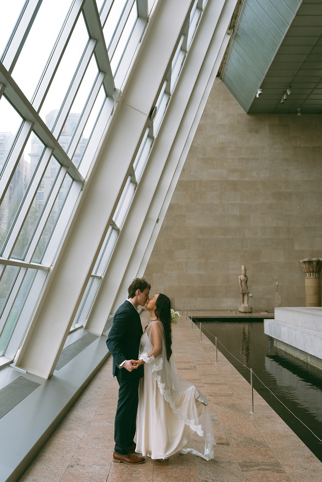 Alex + Bardo NYC Elopement Photos bride and groom kissing next to windows at the Met for elopement photos, shot by elsie goodman, a destination, wedding and NYC elopement photographer