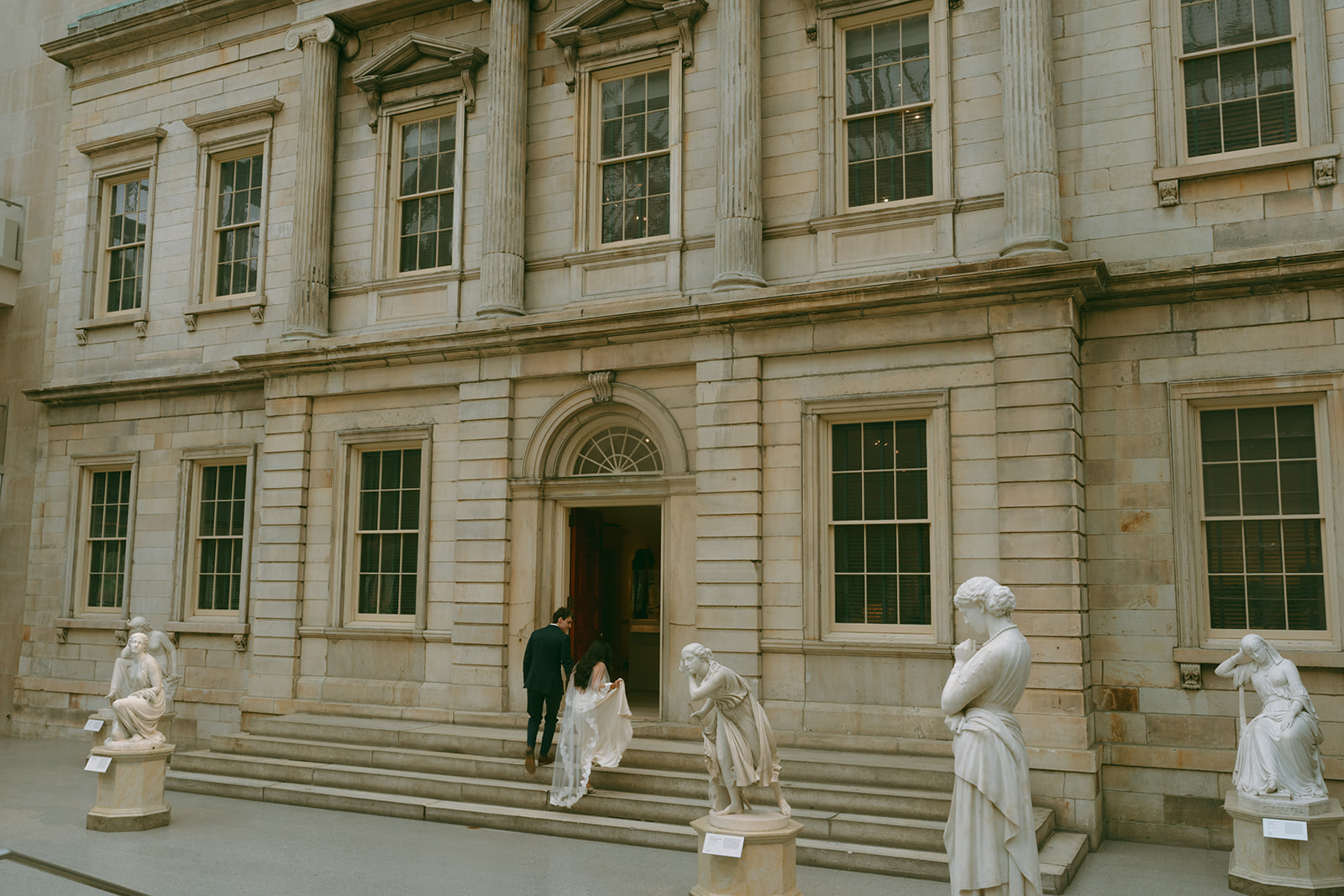 Alex + Bardo NYC Elopement Photos bride and groom surrounded by statues walking into gallery at the Met shot by elsie goodman, a destination, wedding and NYC elopement photographer