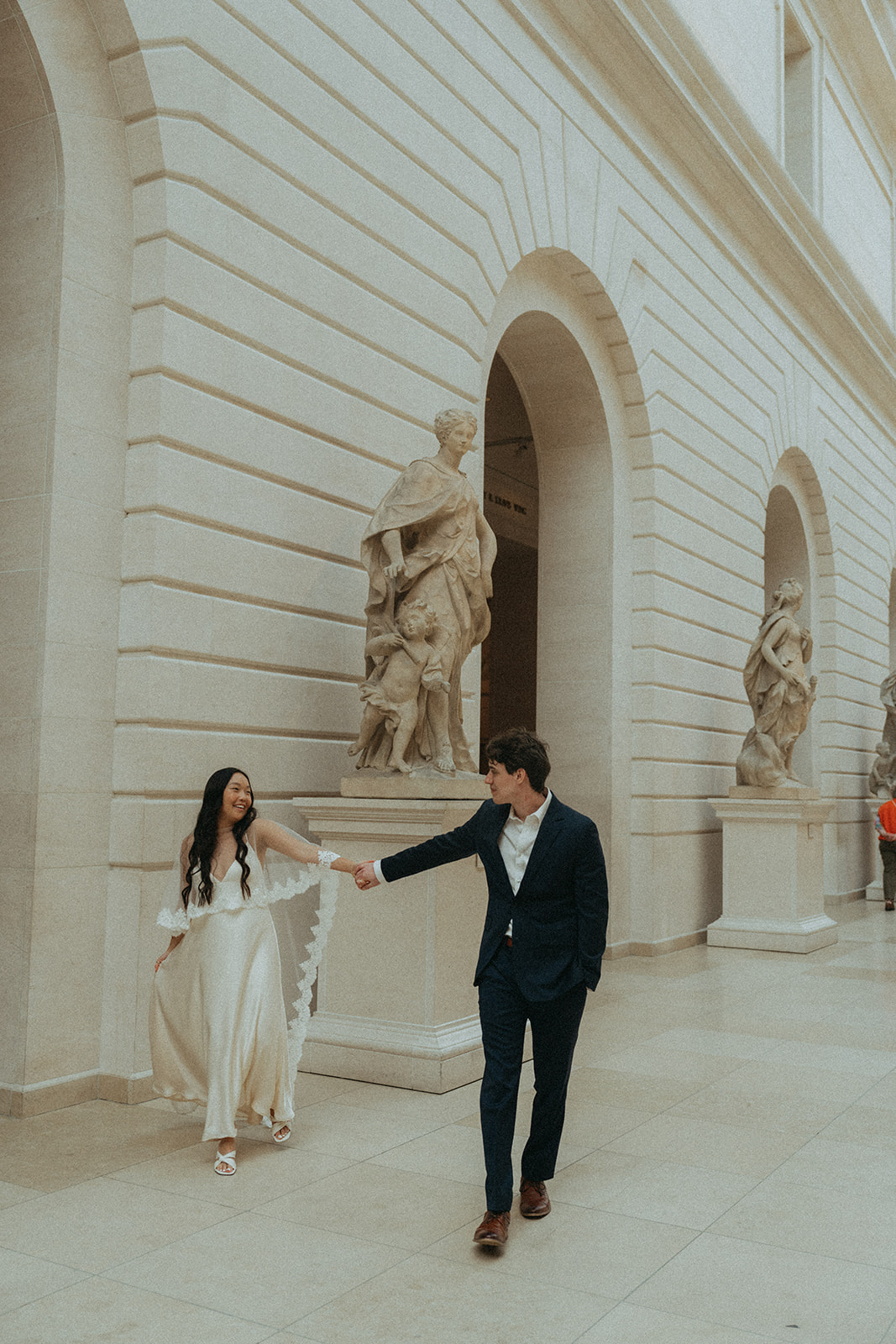 Alex + Bardo NYC Elopement Photos bride and groom walking past sculptures at the Met for elopement photos, shot by elsie goodman, a destination, wedding and NYC elopement photographer