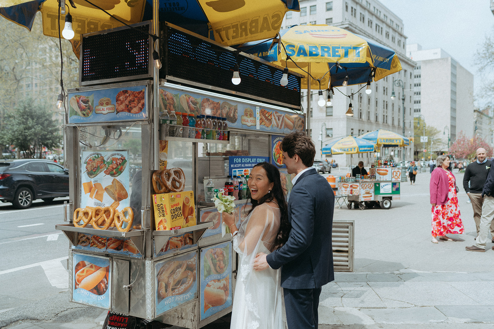Alex + Bardo NYC Elopement Photos bride laughing with groom while getting hot dogs in nyc after eloping at city hall, shot by elsie goodman, a destination, wedding and NYC elopement photographer