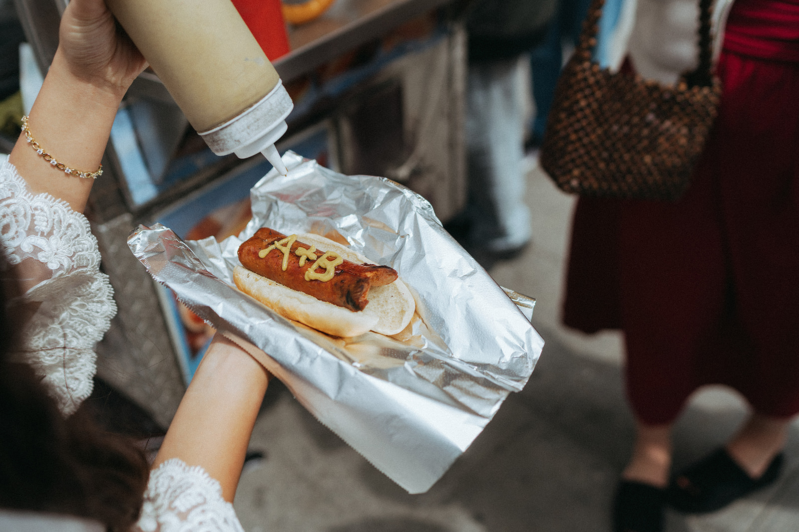 Alex + Bardo NYC Elopement Photos bride putting A+B initials on hot dog with mustard in nyc after eloping at city hall, shot by elsie goodman, a destination, wedding and NYC elopement photographer