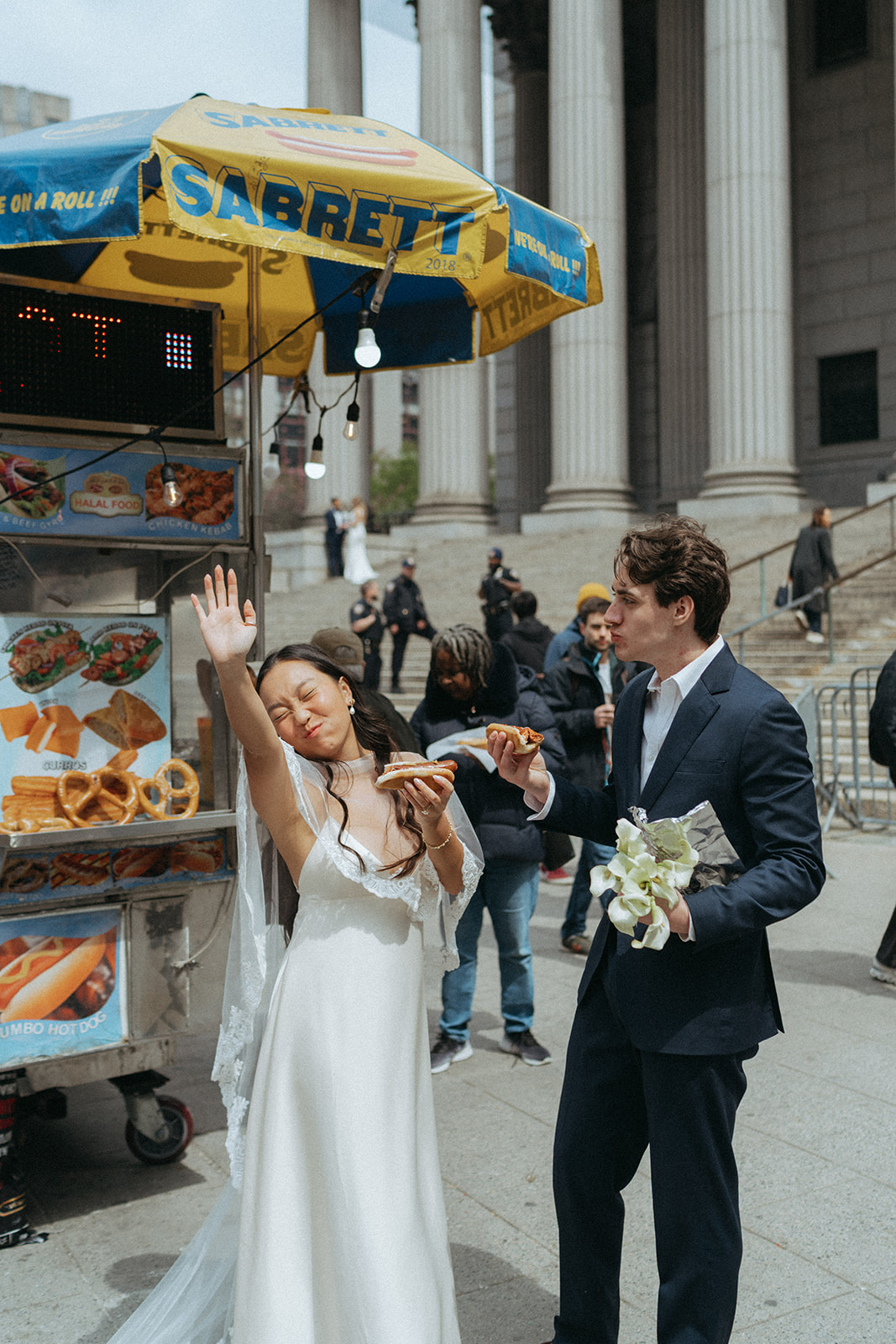 Alex + Bardo NYC Elopement Photos bride's hand in her air and groom next to her eating hot dogs in nyc after eloping at city hall, shot by elsie goodman, a destination, wedding and NYC elopement photographer