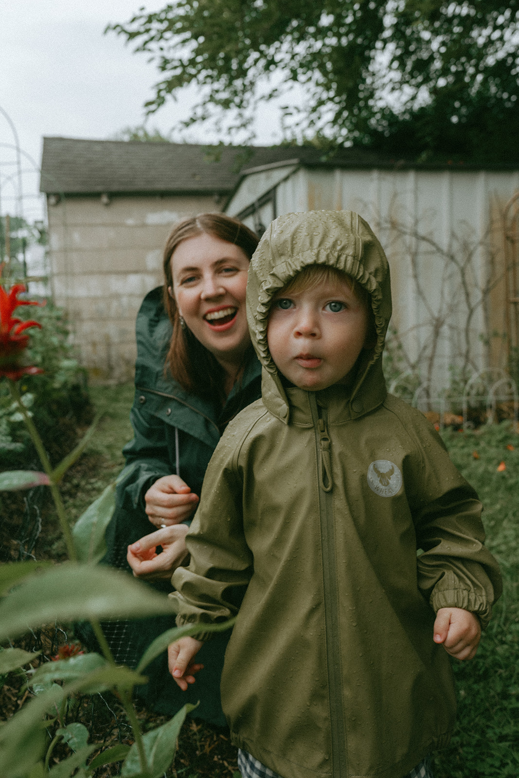 Mom smiling crouched behind her kid as he makes a funny face at the camera by maternity, family, and wedding photographer Elsie Goodman.
