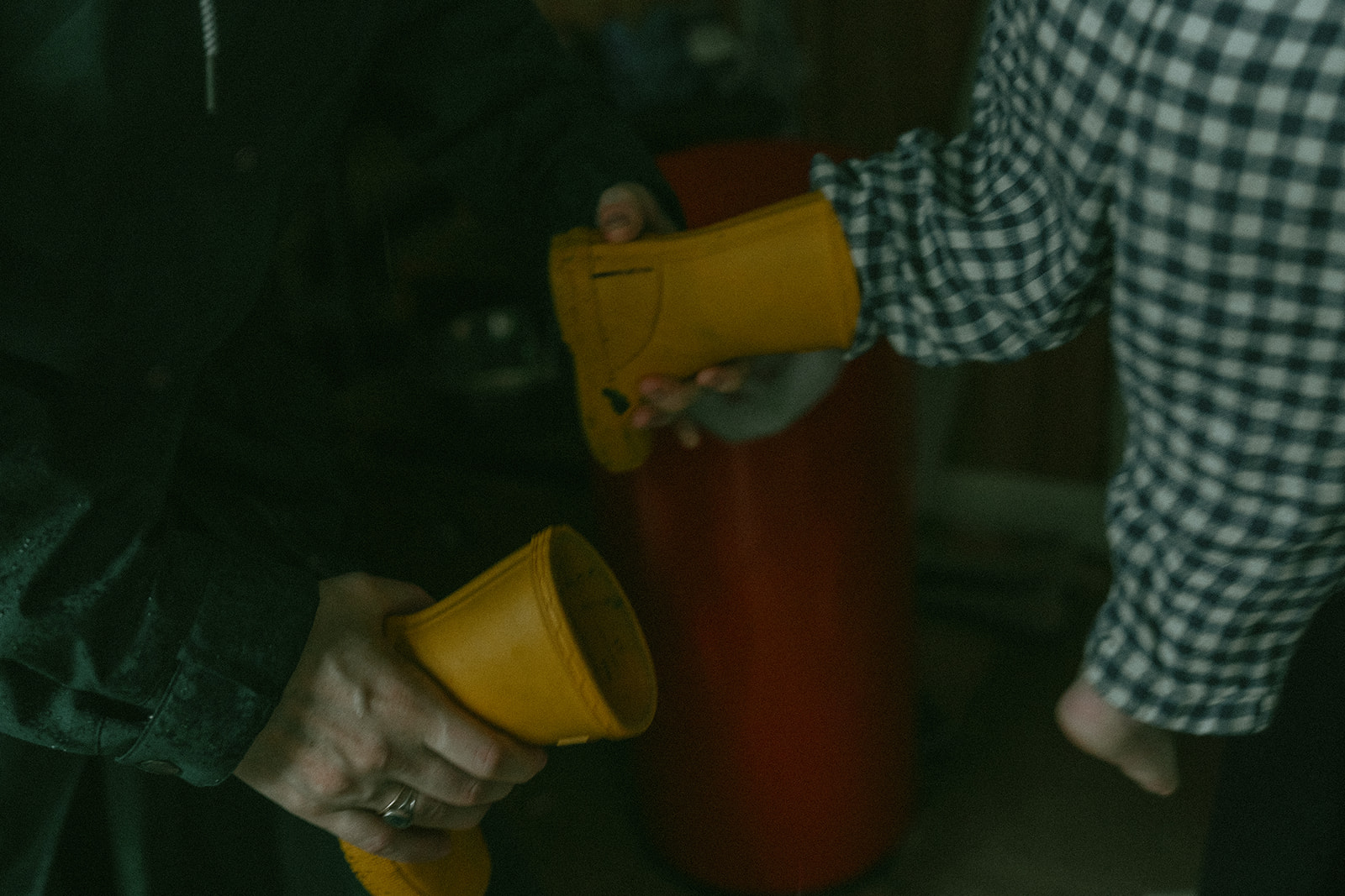 Mom helping take of child's yellow rain boots by maternity, family, and wedding photographer Elsie Goodman.