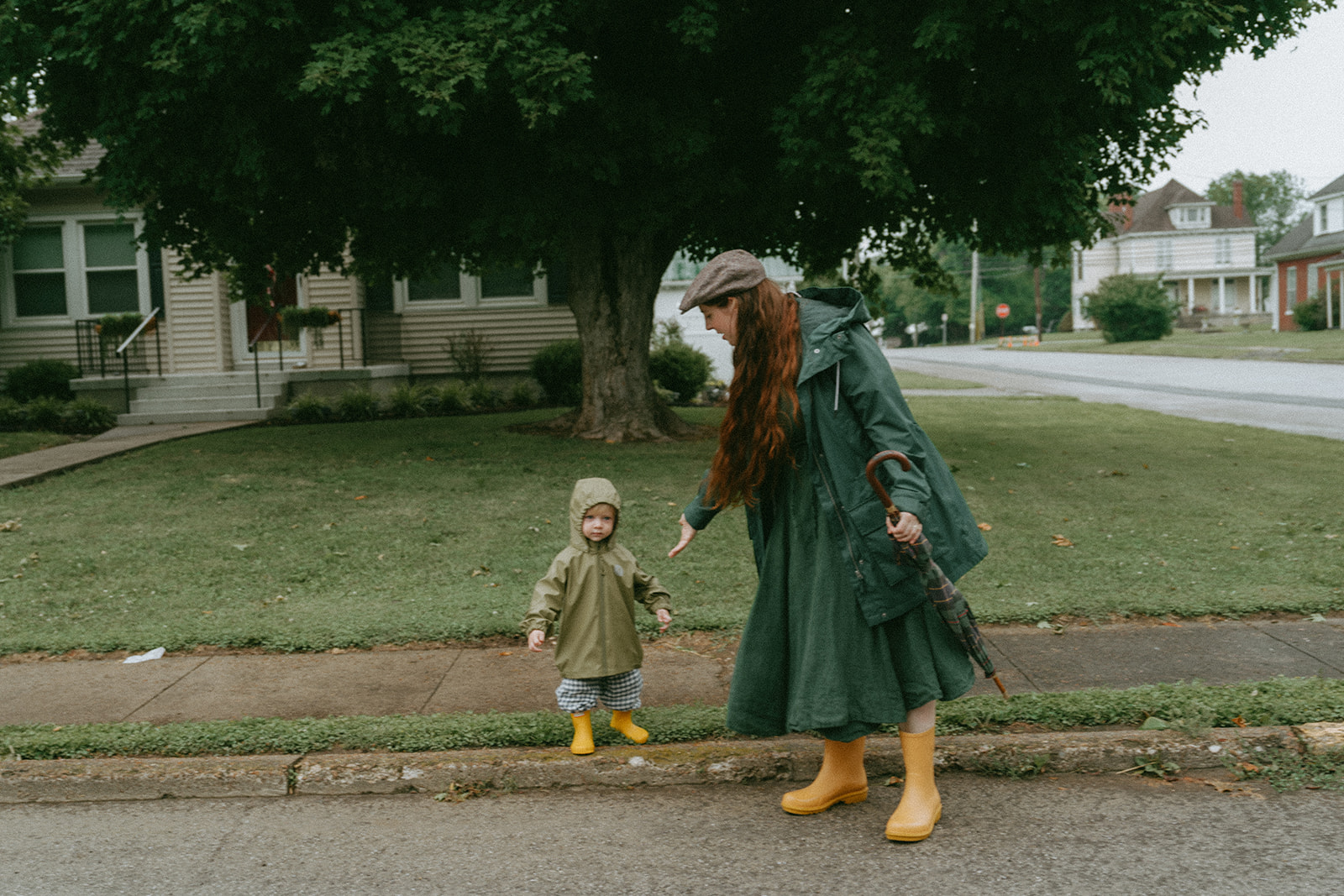 mother and child both in green rain jackets and yellow rain boots by maternity, family, and wedding photographer Elsie Goodman.