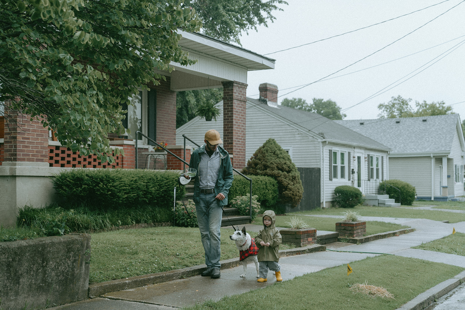 Dad walks the dog down the street with his child by maternity, family, and wedding photographer Elsie Goodman.