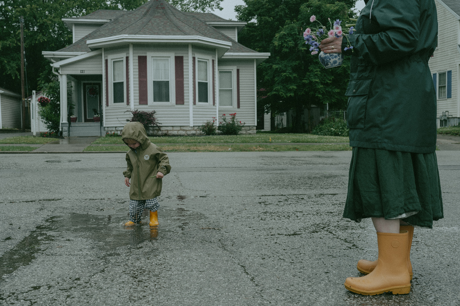 Child plays in puddle as mom watches by maternity, family, and wedding photographer Elsie Goodman.