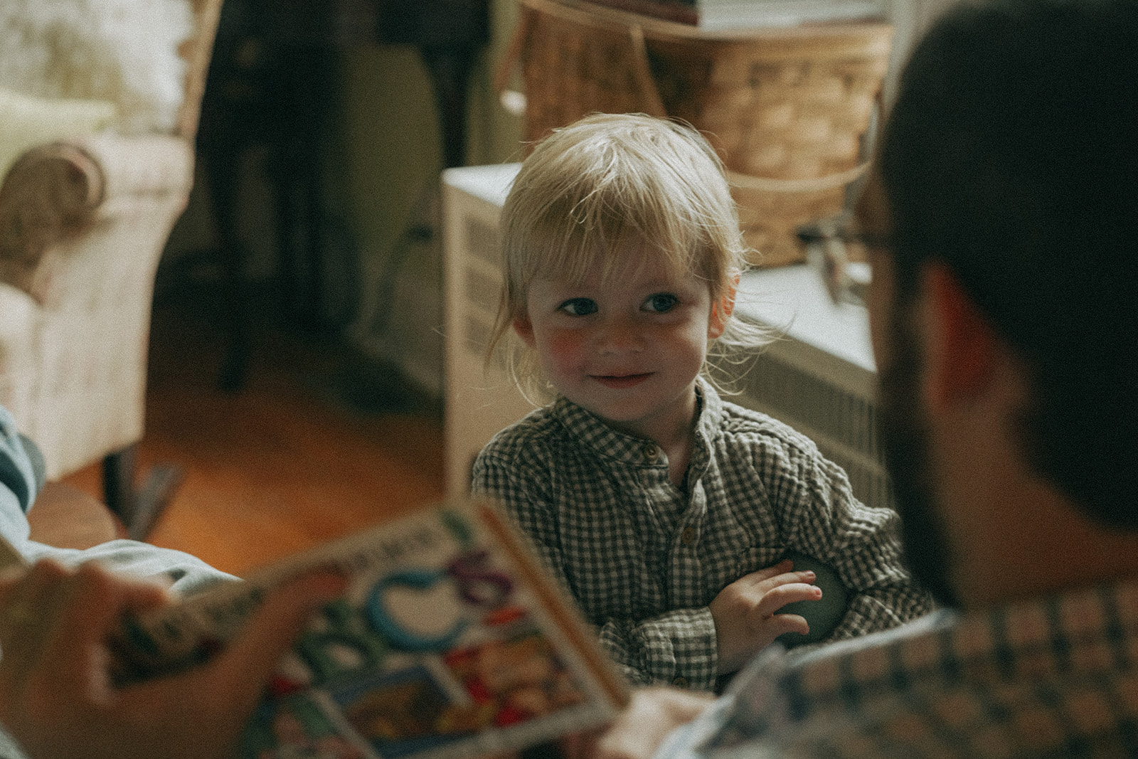 Close up of Dad reading a book to his son Mom, Dad, child and dog all sit on the front steps of their house by maternity, family, and wedding photographer Elsie Goodman.