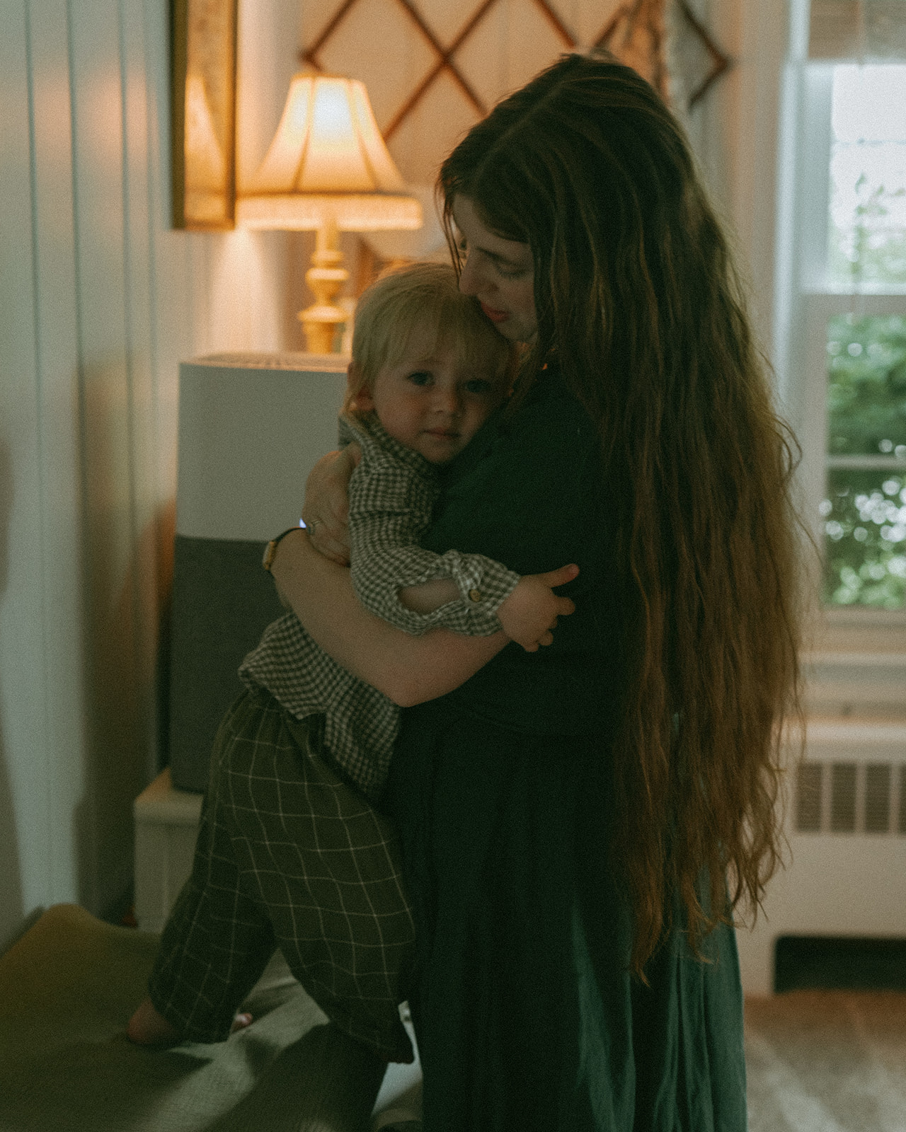 Mom hugging her child in their living room Mom, Dad, child and dog all sit on the front steps of their house by maternity, family, and wedding photographer Elsie Goodman.