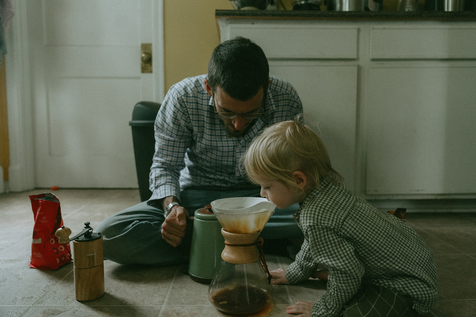 Dad and child sit on the floor making coffee in a Chemex by maternity, family, and wedding photographer Elsie Goodman.