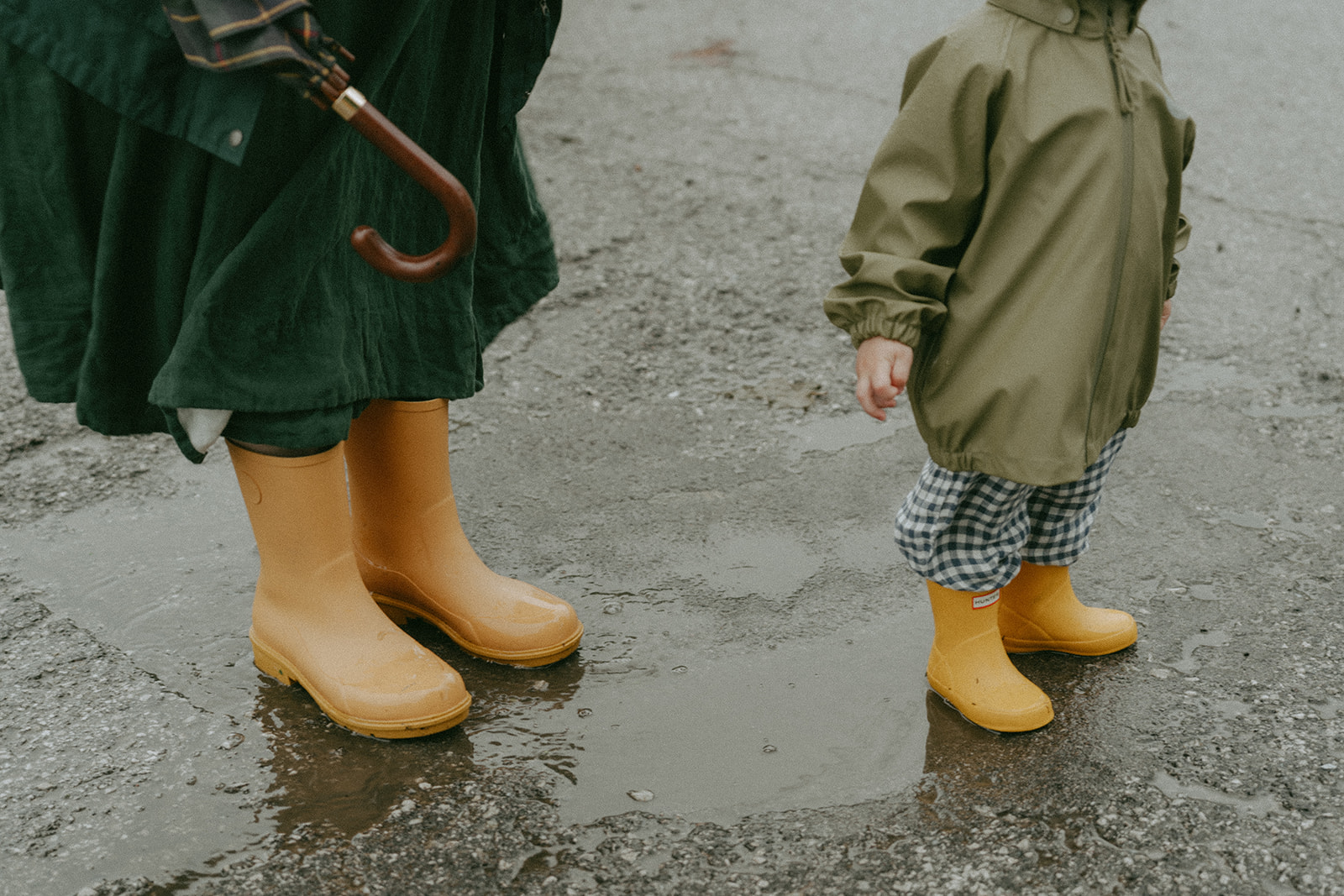 Close up of mom and kid's matching yellow rain boots by maternity, family, and wedding photographer Elsie Goodman.