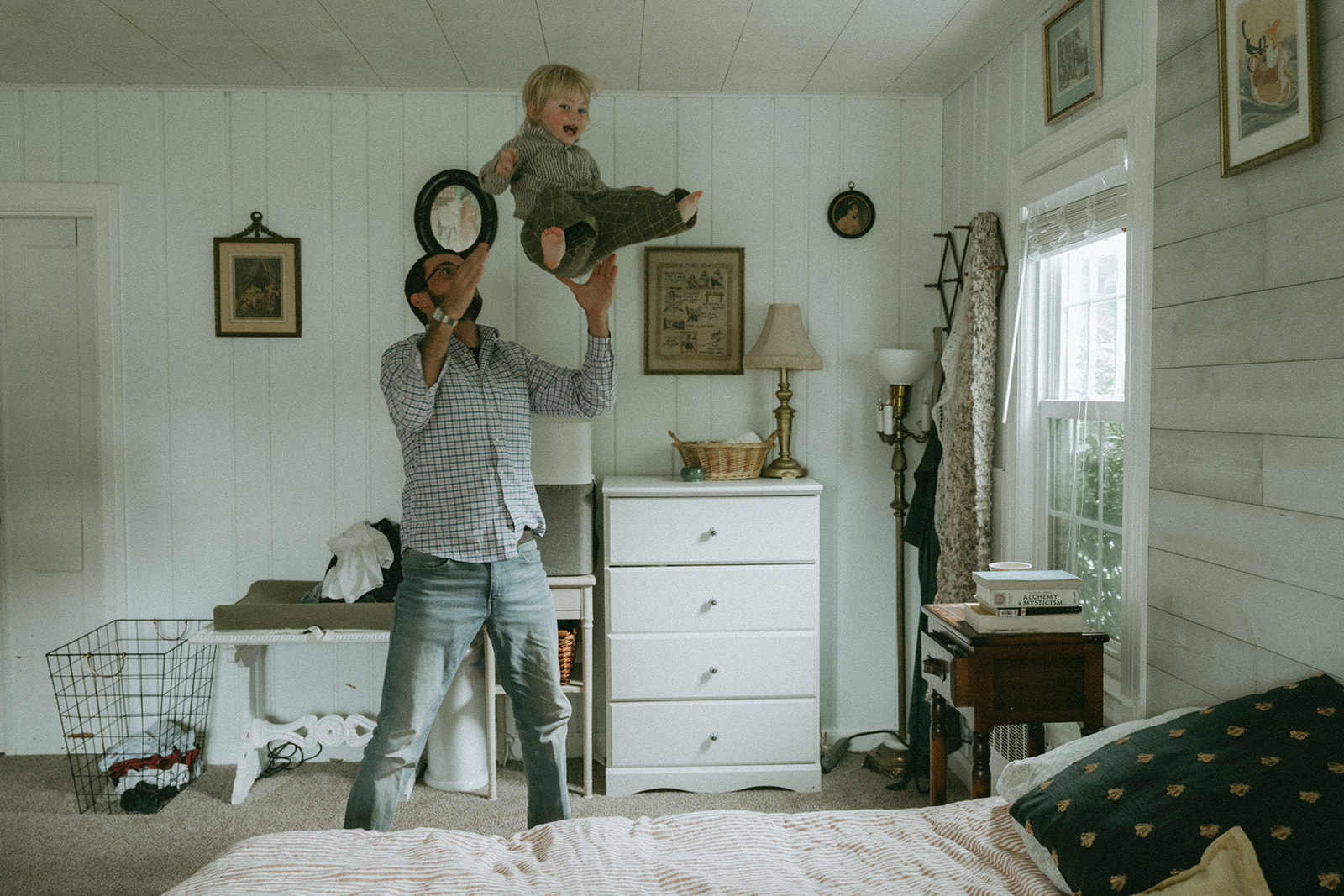 Dad tossing his child up in the air, playing by maternity, family, and wedding photographer Elsie Goodman.