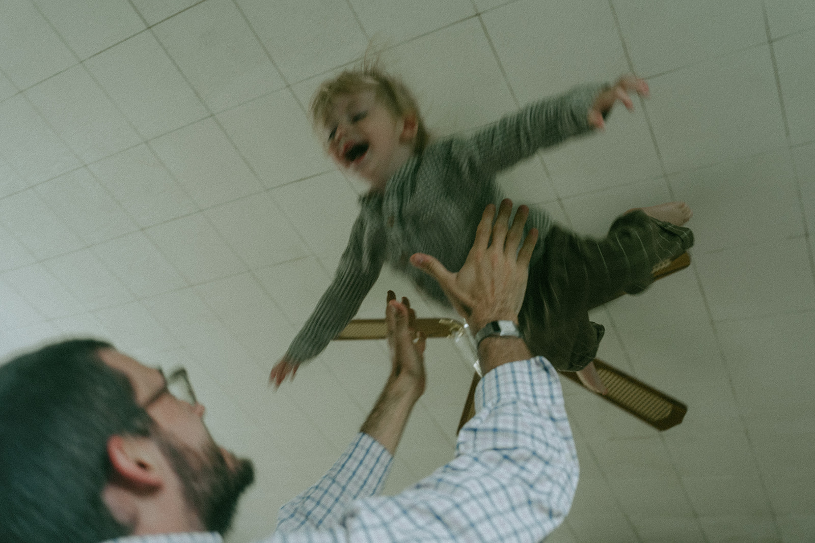 Dad tossing his kid up, playfully as the child laughs by maternity, family, and wedding photographer Elsie Goodman.