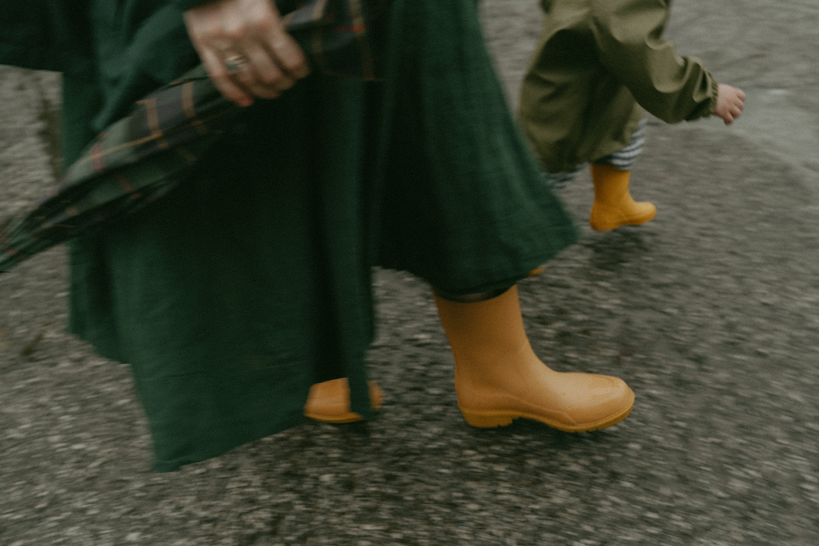 Mom and child walking down a rainy street in matching yellow rain boots by maternity, family, and wedding photographer Elsie Goodman.
