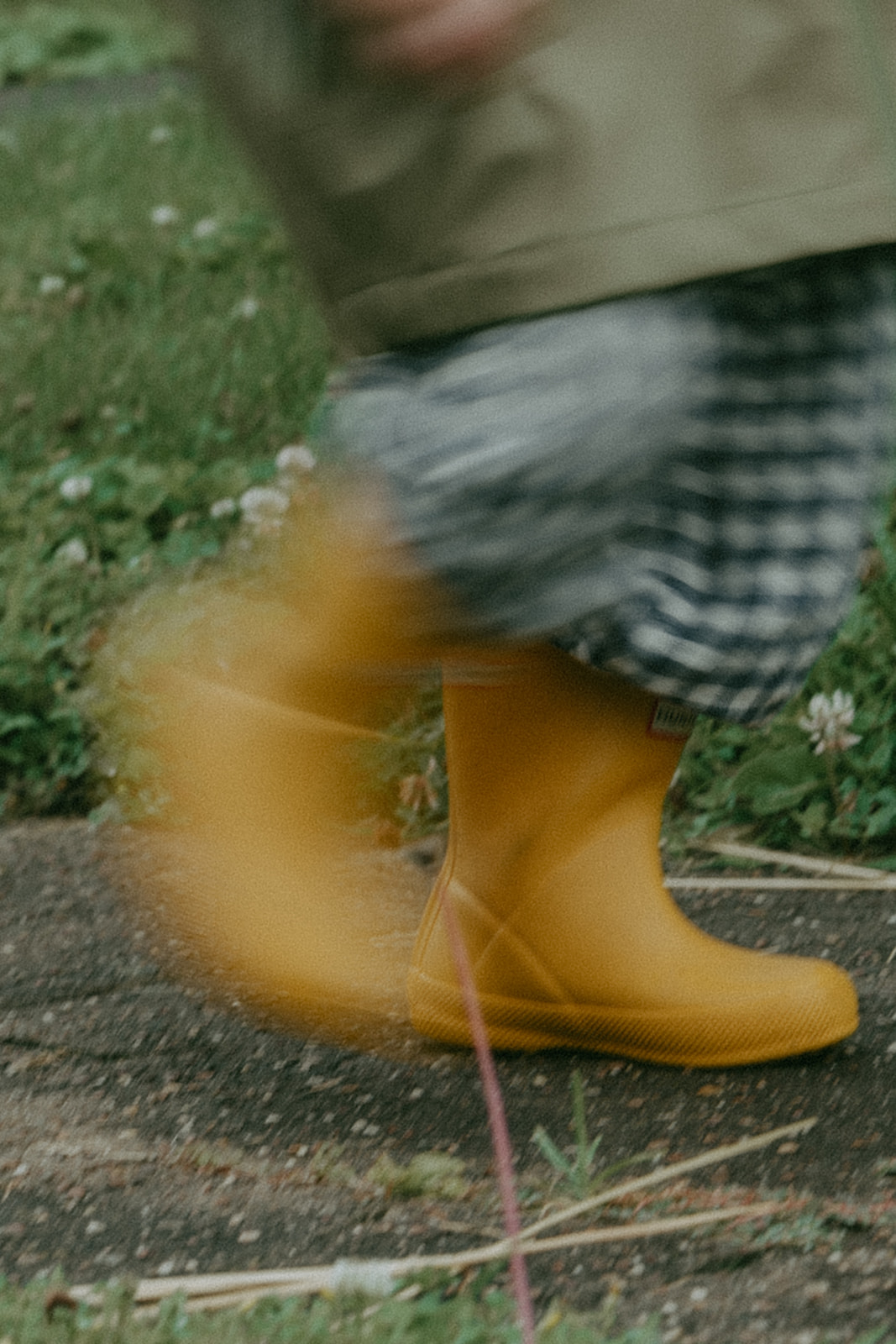 Action shot of a child running in yellow rain boots by maternity, family, and wedding photographer Elsie Goodman.