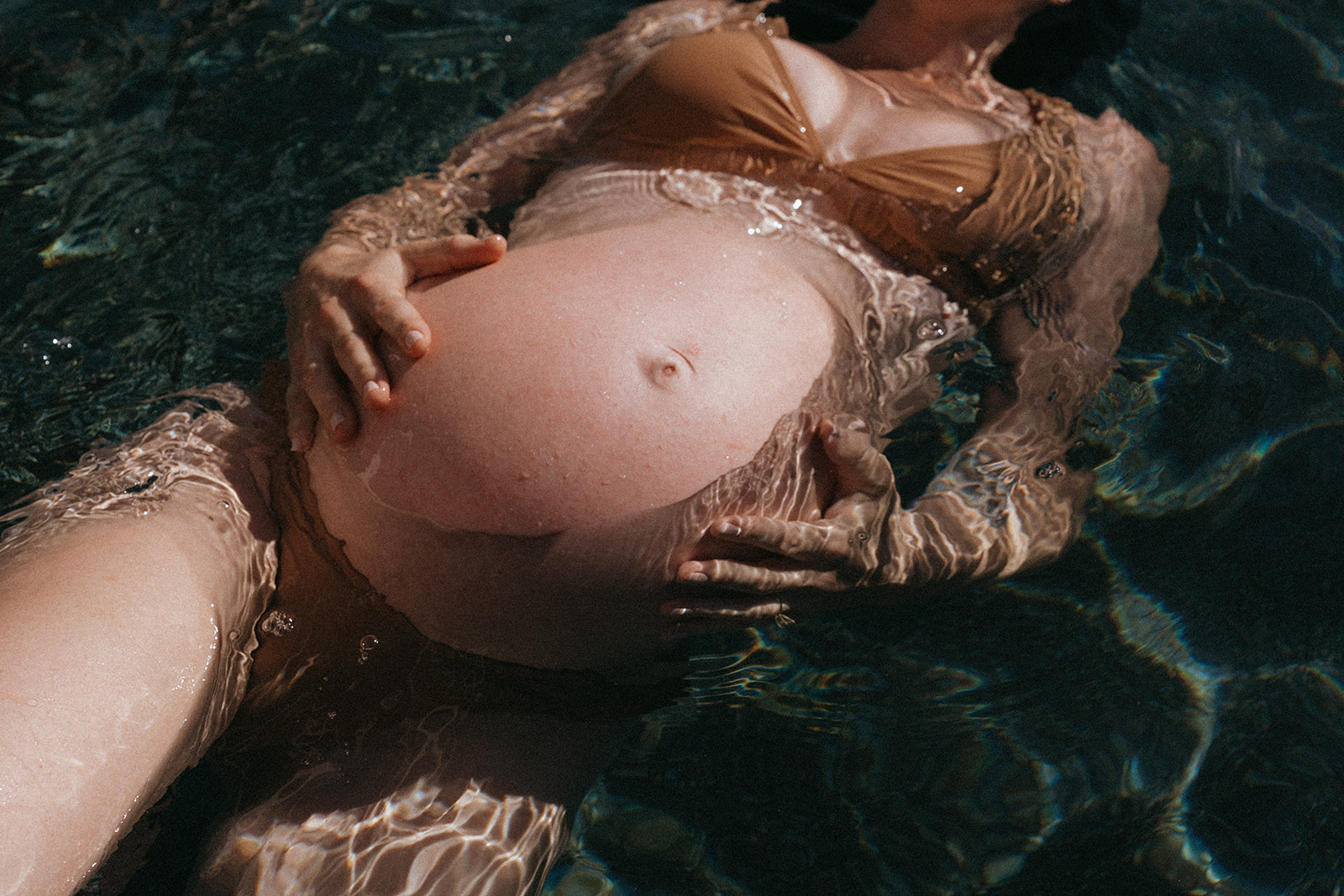 Pregnant women in a bikini photographed in water by maternity photographer Elsie Goodman.