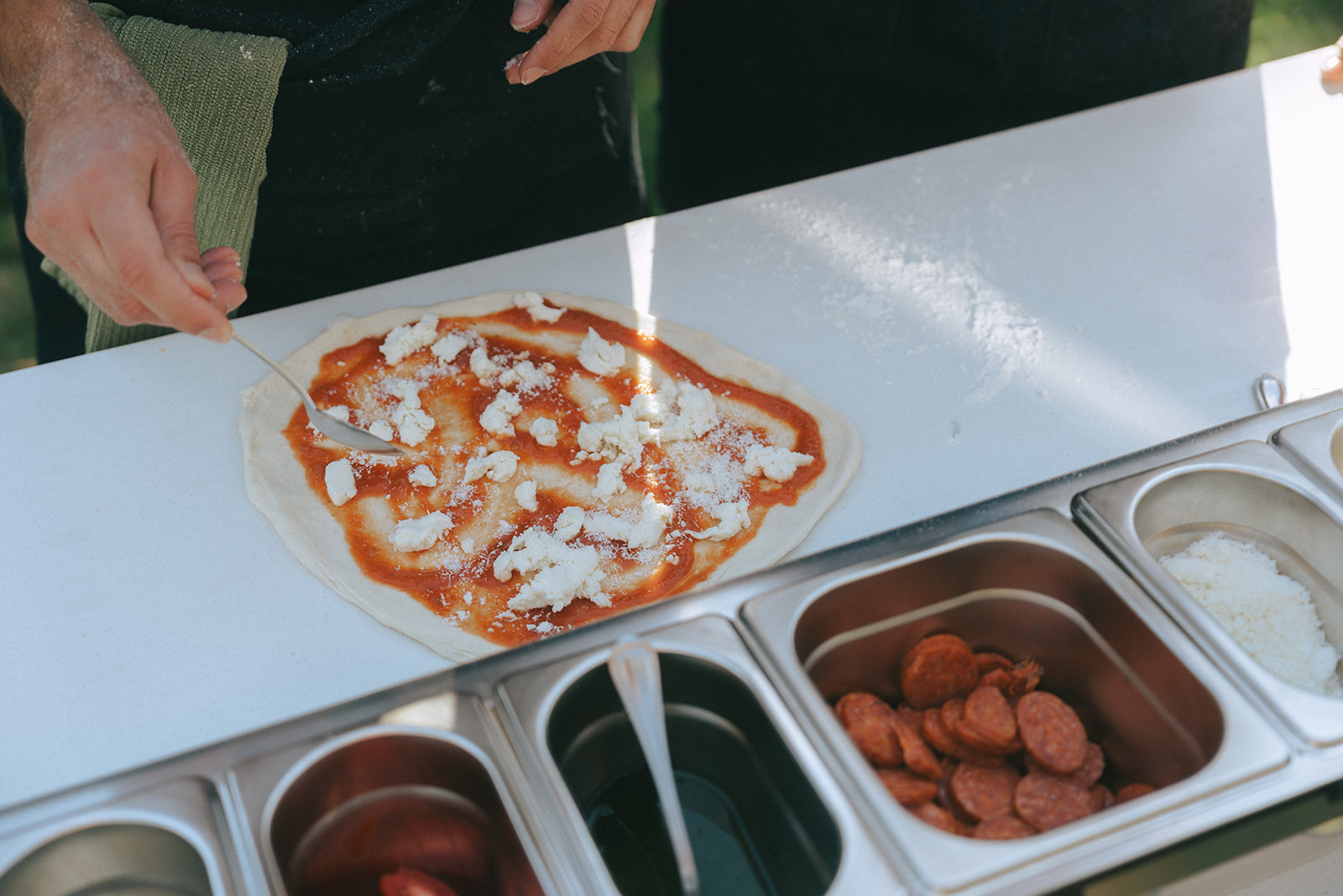 Close up of a pizza being made in the backyard by couples photographer, Elsie Goodman.