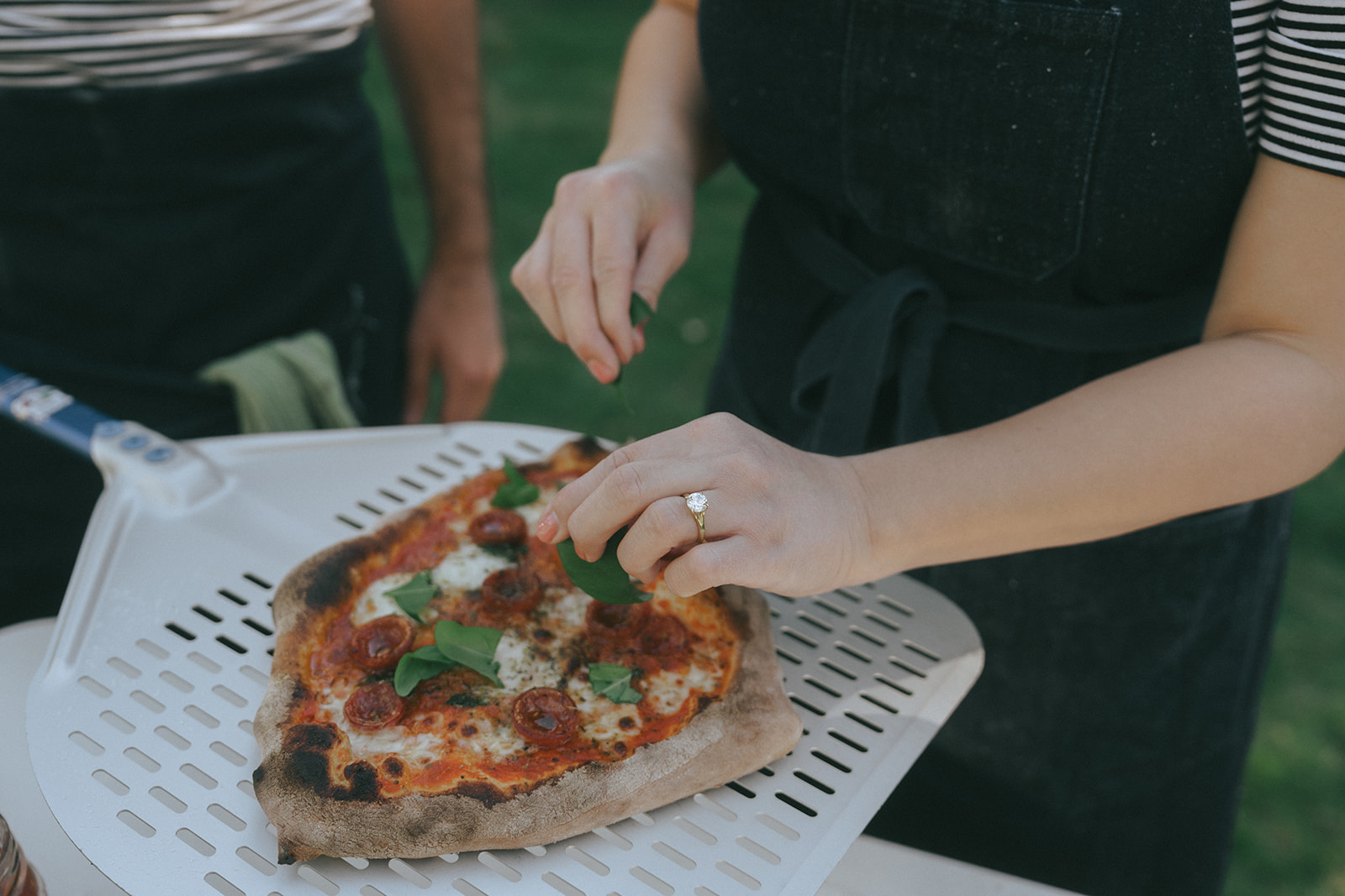 Photo of a woman putting fresh basil on a pizza by couples photographer, Elsie Goodman.