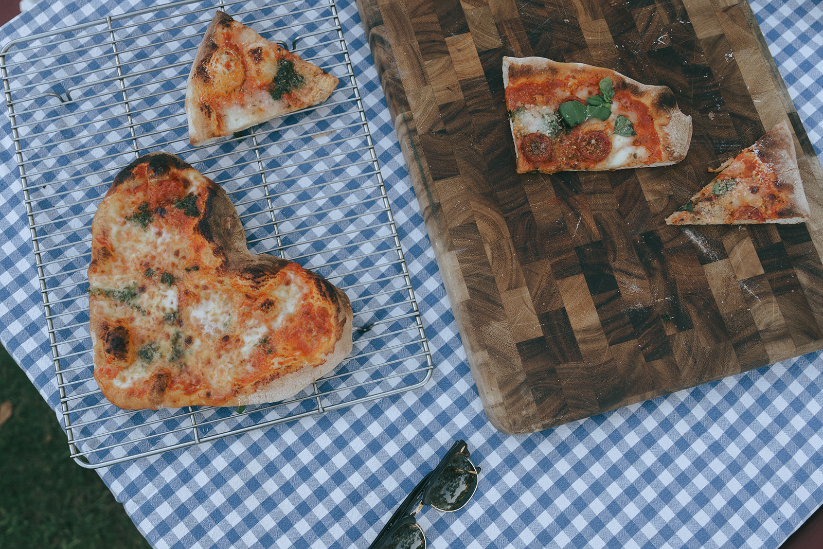 Top down shot of a heart shaped pizza and a piece on a wood cutting board by the wedding and couples photographer, Elsie Goodman.