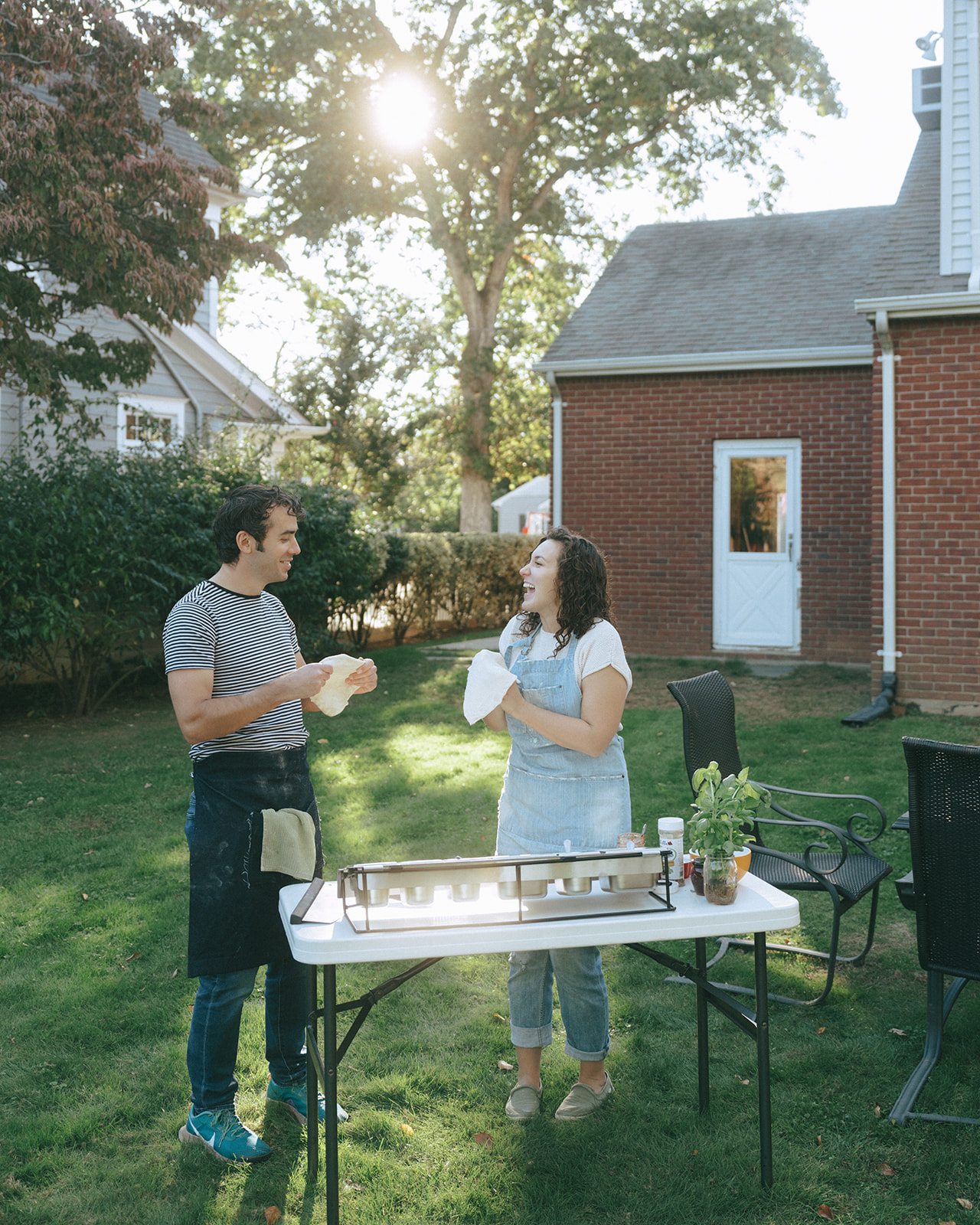 Couple stretching pizza dough while making pizzas outside by wedding and couples photographer Elsie Goodman.
