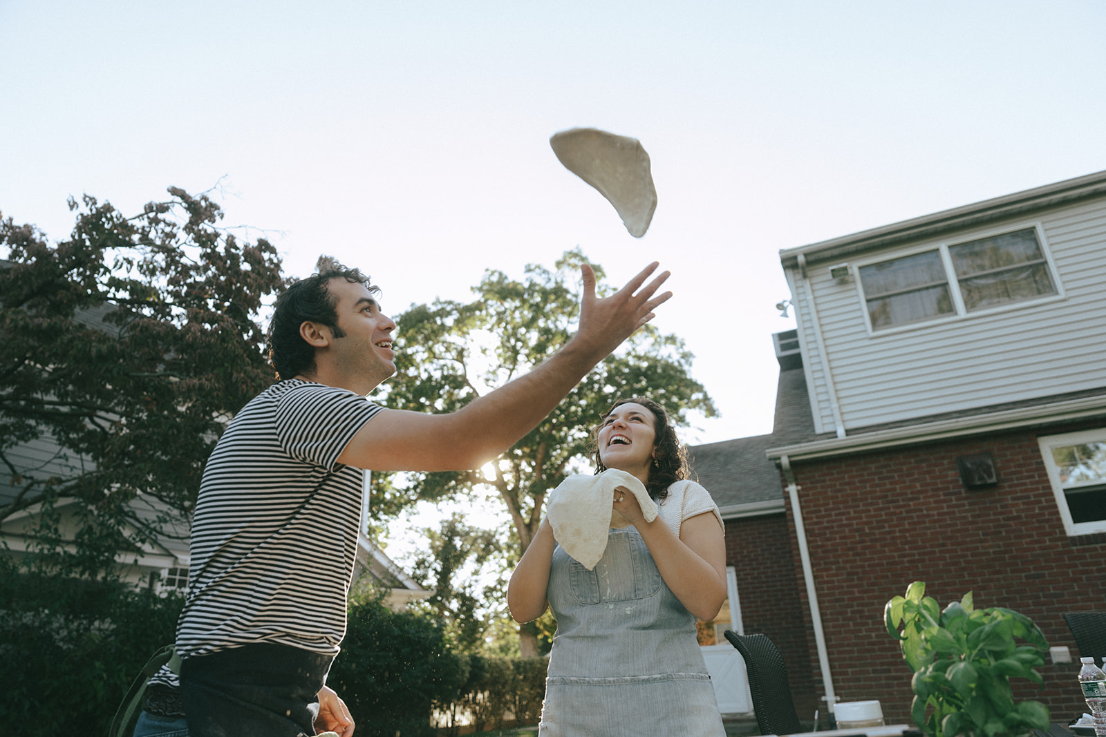 Couple throwing pizza dough in the air outside by wedding and couples photographer Elsie Goodman.