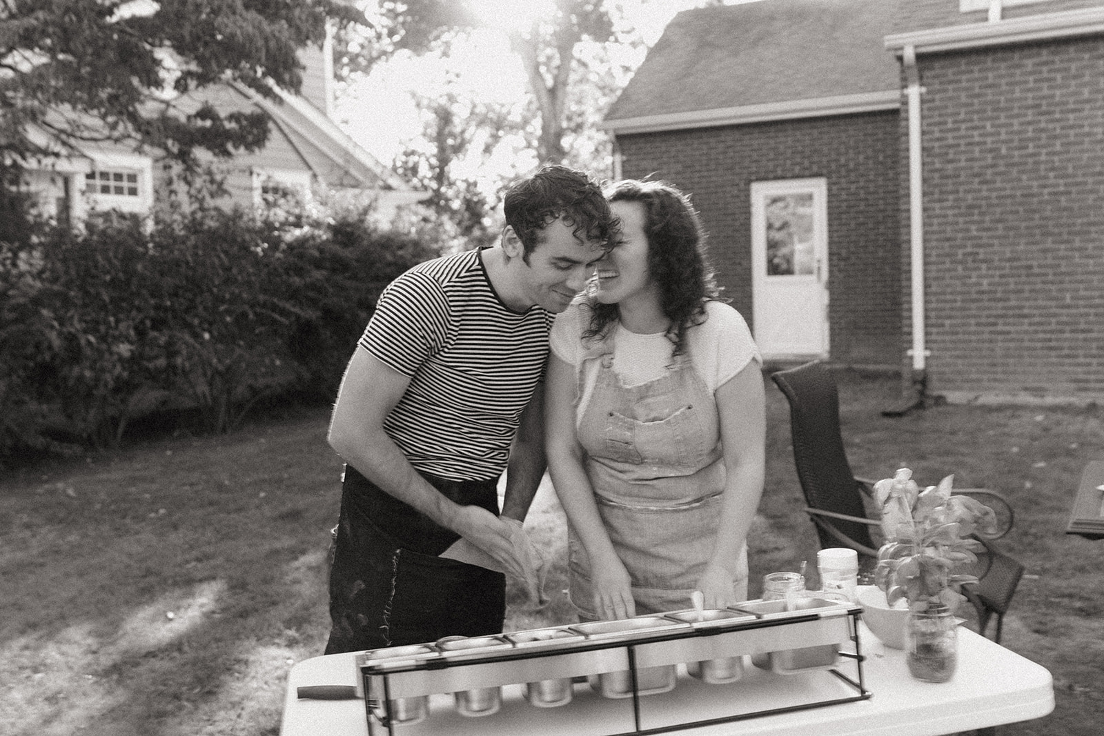 Black and white photo of a couple making pizza outside by wedding and couples photographer Elsie Goodman.