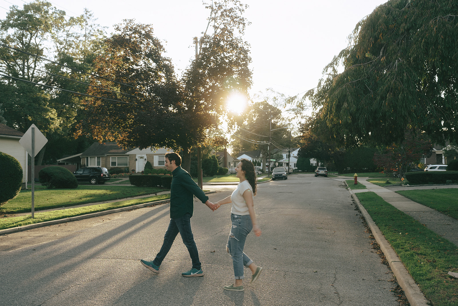 photo of a couple walking across a suburban street, hand in hand, during the golden hour by wedding and couples photographer Elsie Goodman.