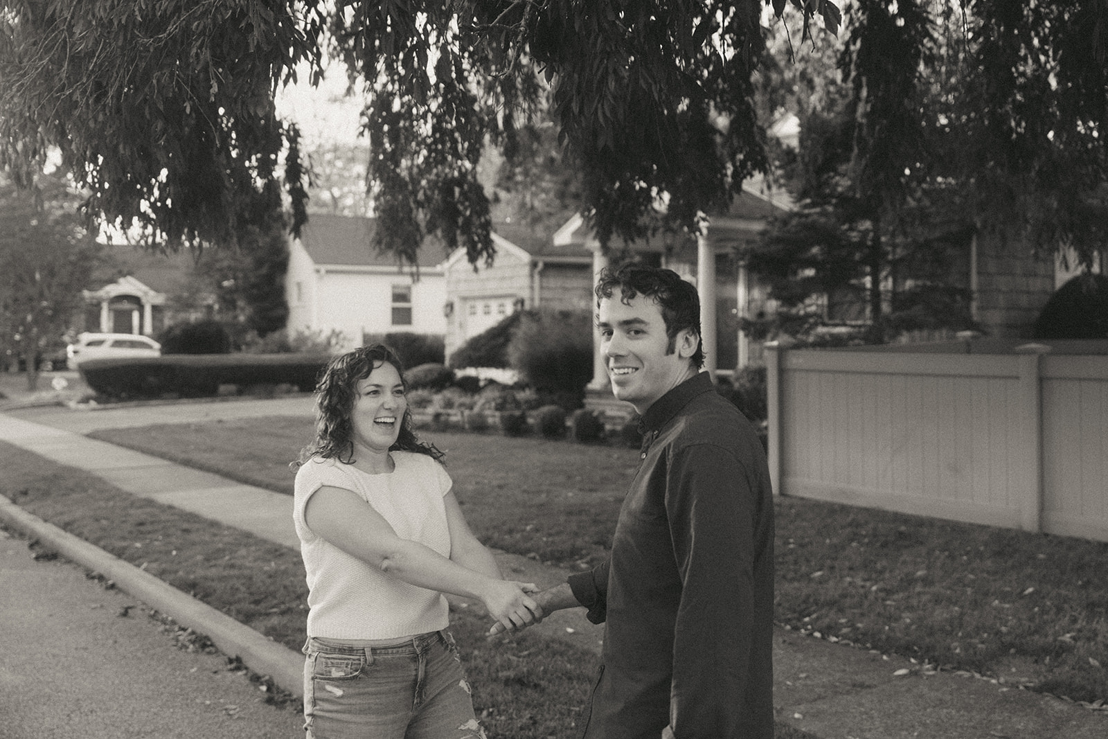 Black and white photo of a couple on the street, smiling by wedding and couples photographer Elsie Goodman.