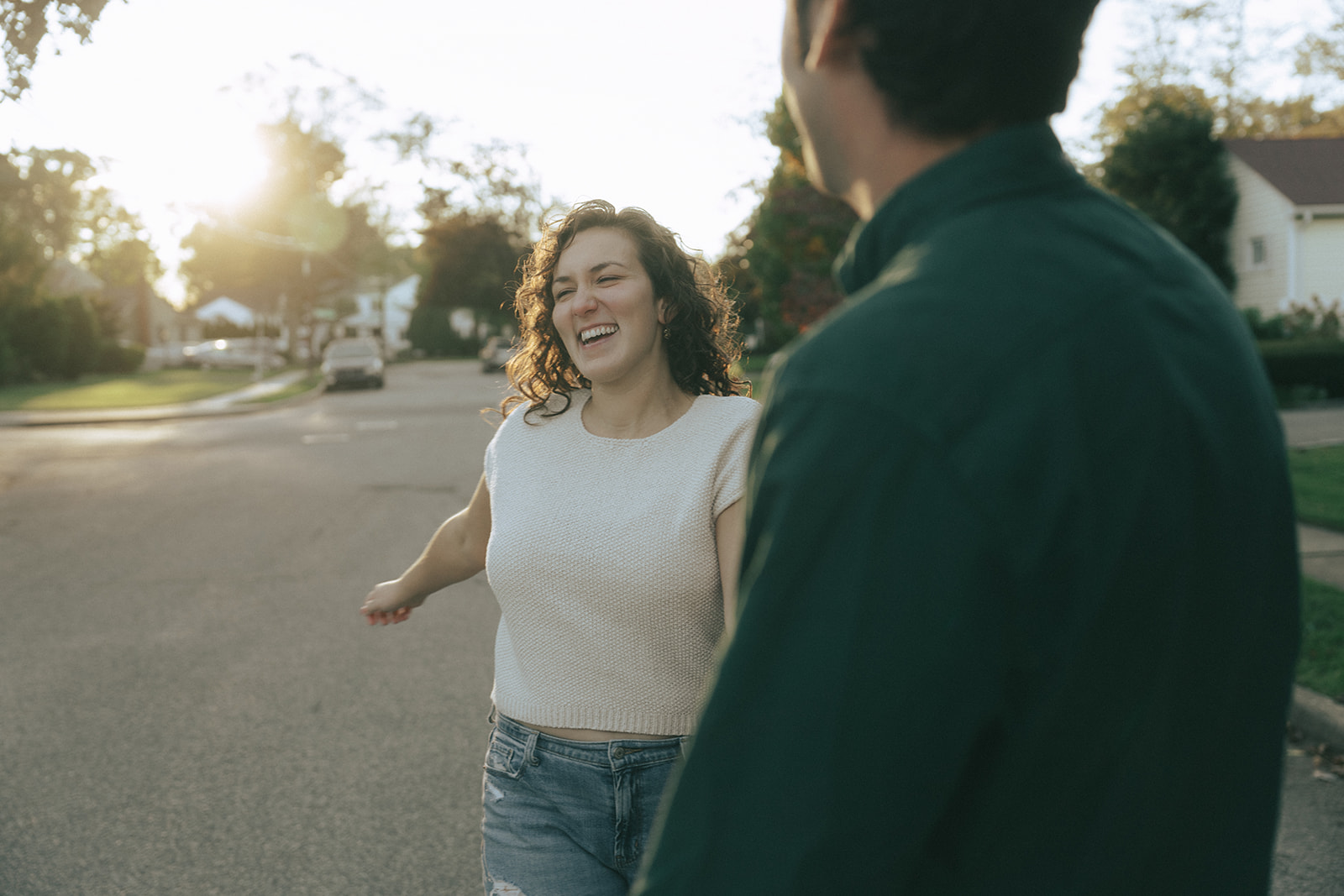 Woman smiling holding the hand of a man, taken during the golden hour by wedding and couples photographer Elsie Goodman.