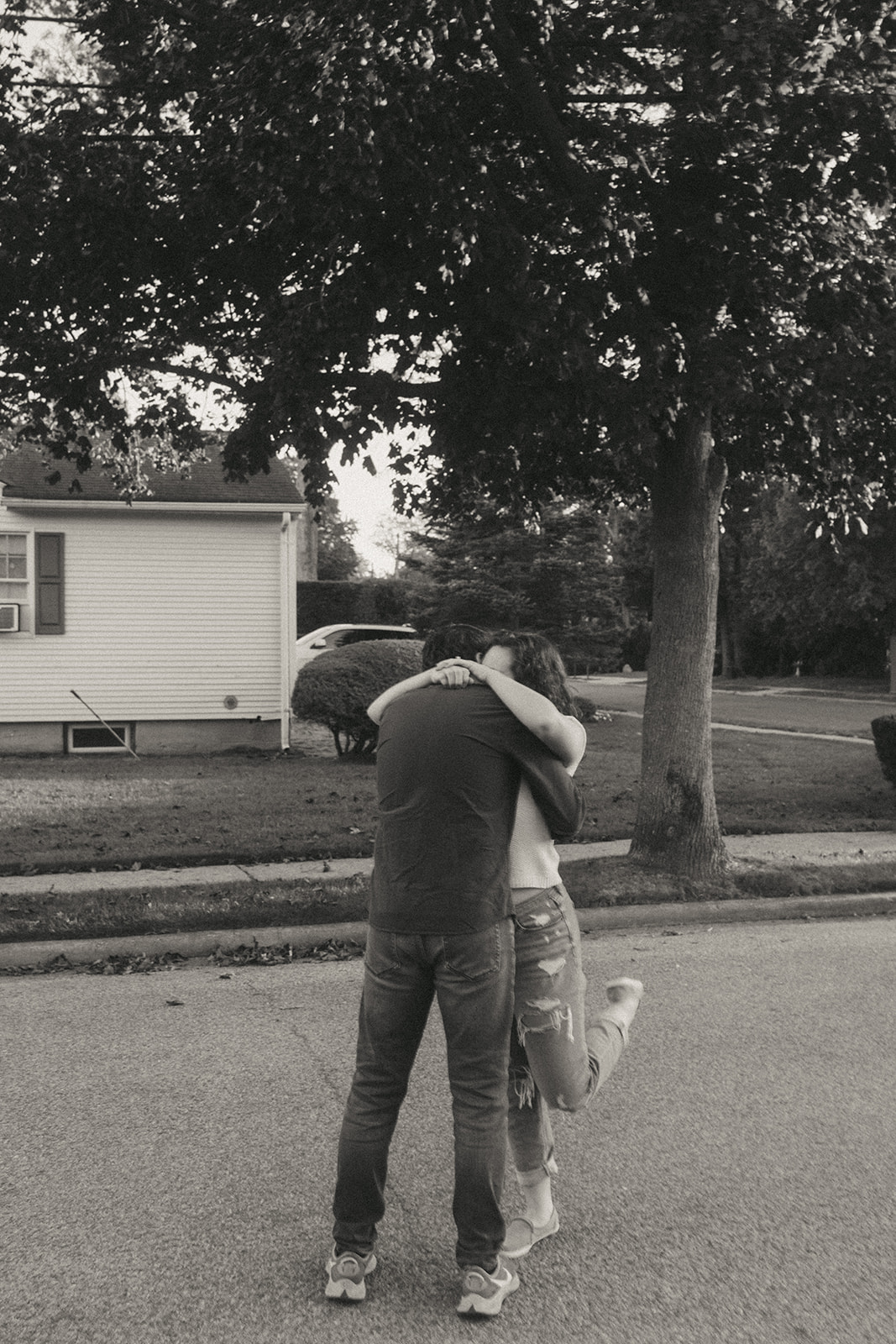 Black and white photo of a couple hugging enthusiastically by wedding and couples photographer Elsie Goodman.