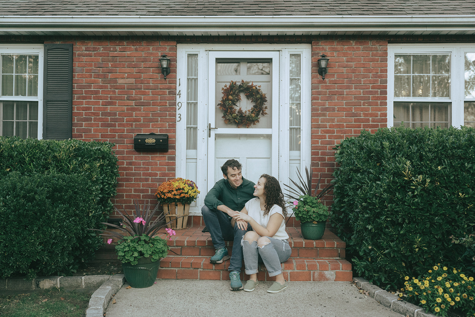 couple looking at each other sitting on the steps of their house by wedding and couples photographer Elsie Goodman.