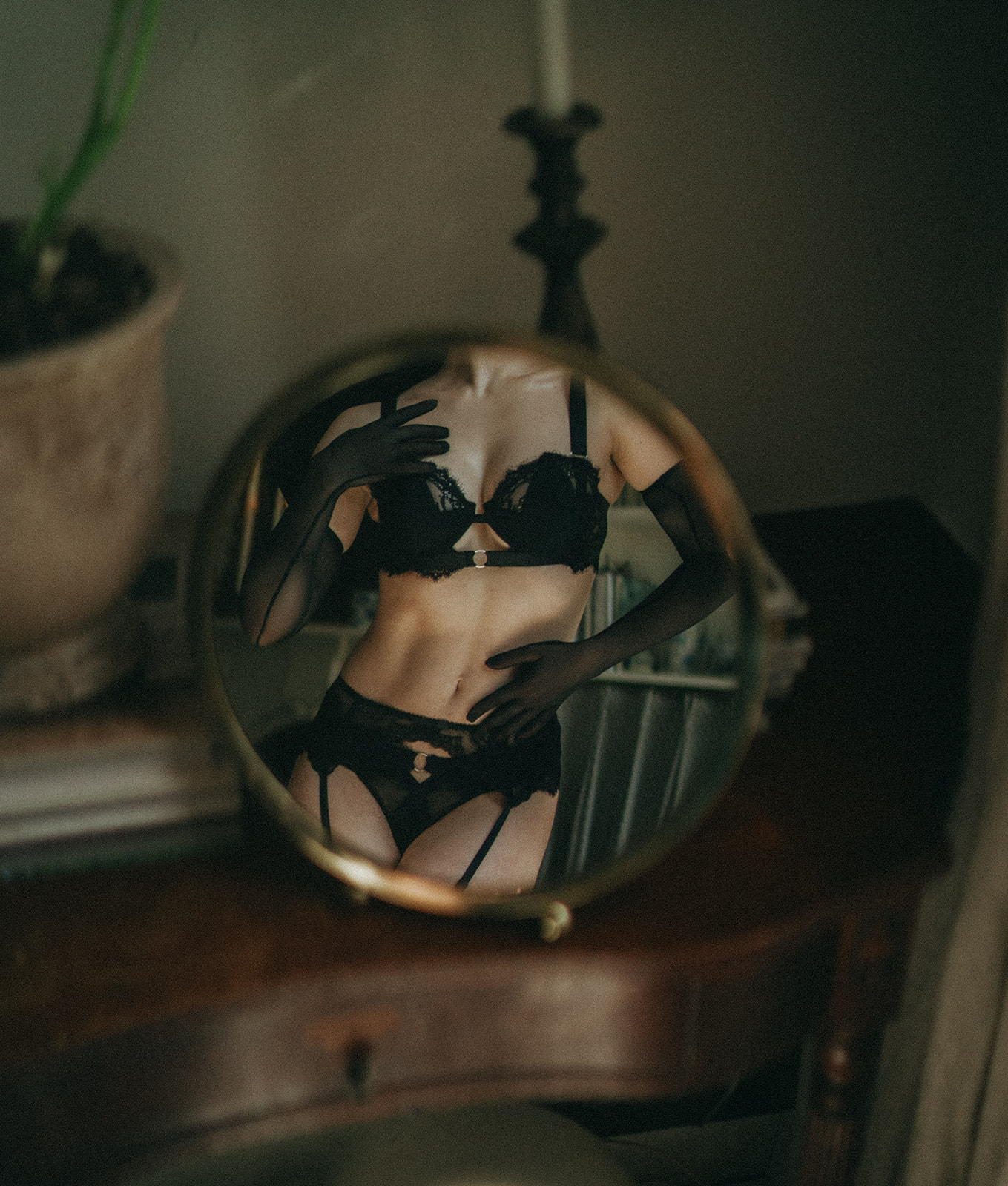Black lingerie reflected in a mirror on a dresser, a moody styling detail for a boudoir session