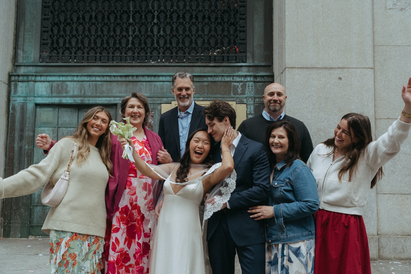 Group of guests cheering with the couple outside the New York City Hall building