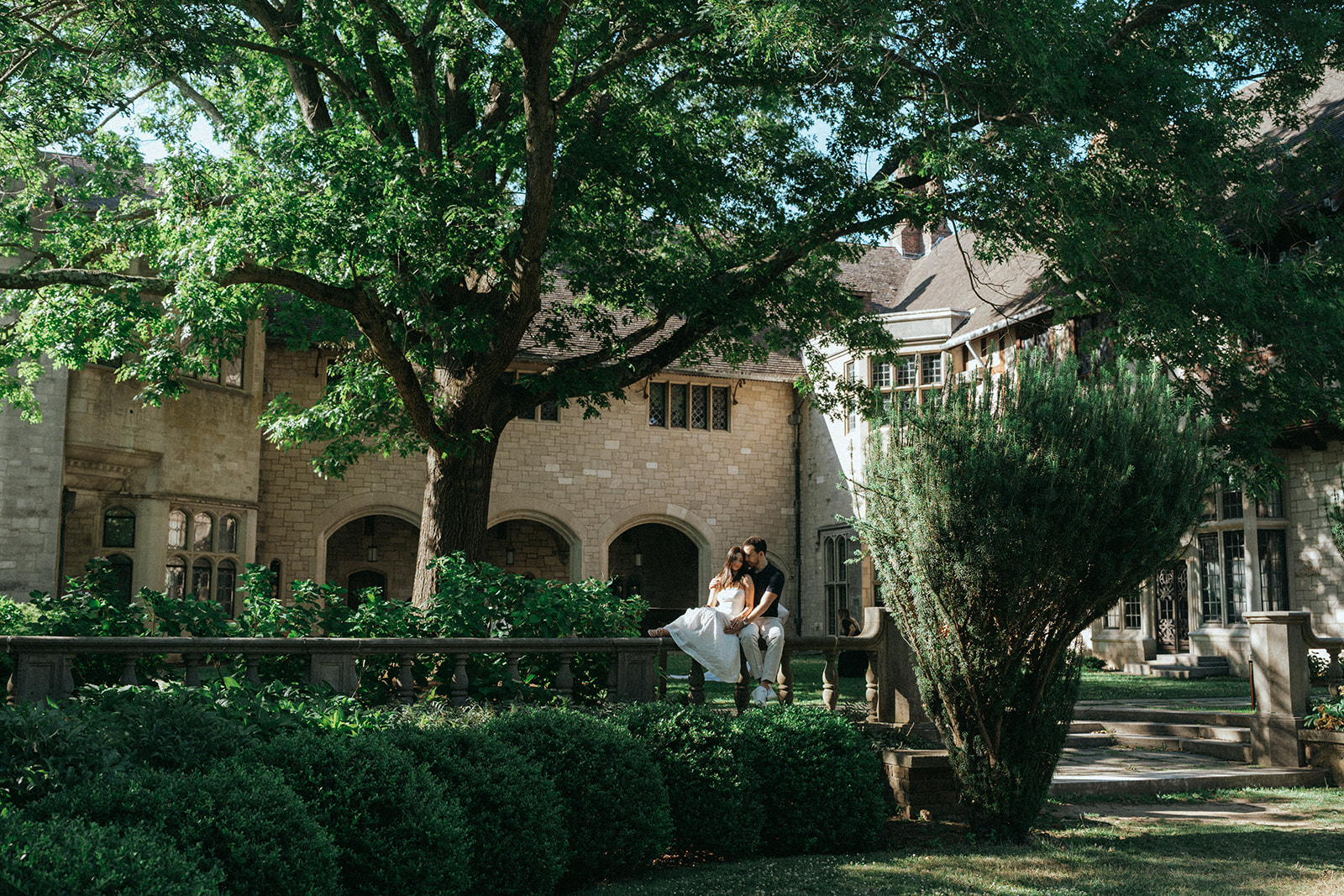 Man and woman sitting on ledge in Planting Fields Arboretum after proposal