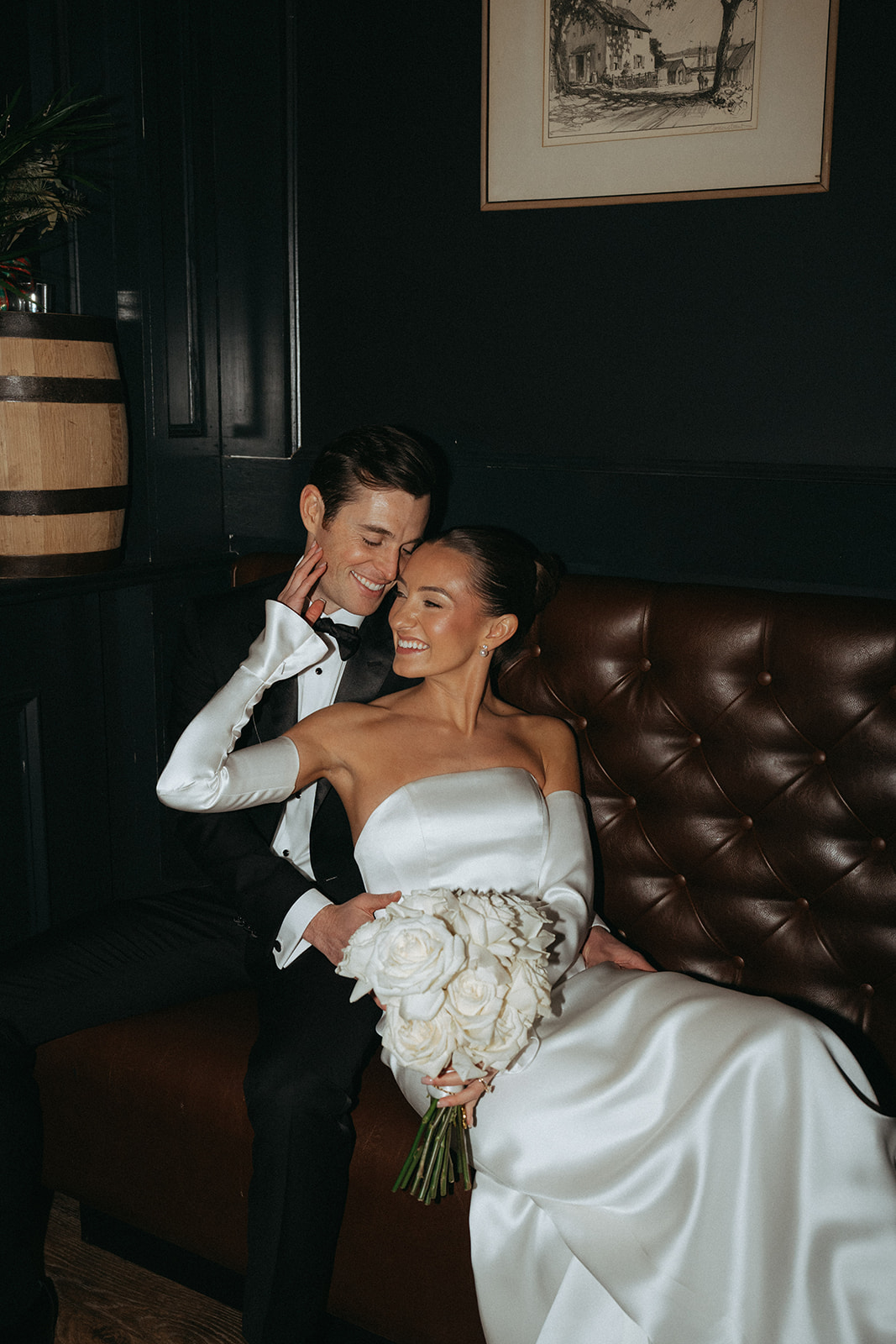 Bride and groom on a leather couch in moody light, an editorial wedding portrait shot list image