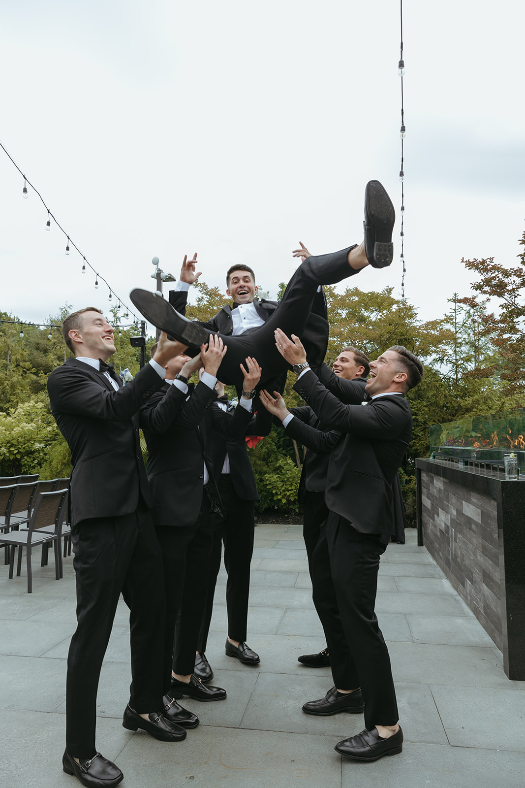 Groomsmen in black tuxedos leaping in the air, the kind of joyful moment a wedding photography shot list should capture