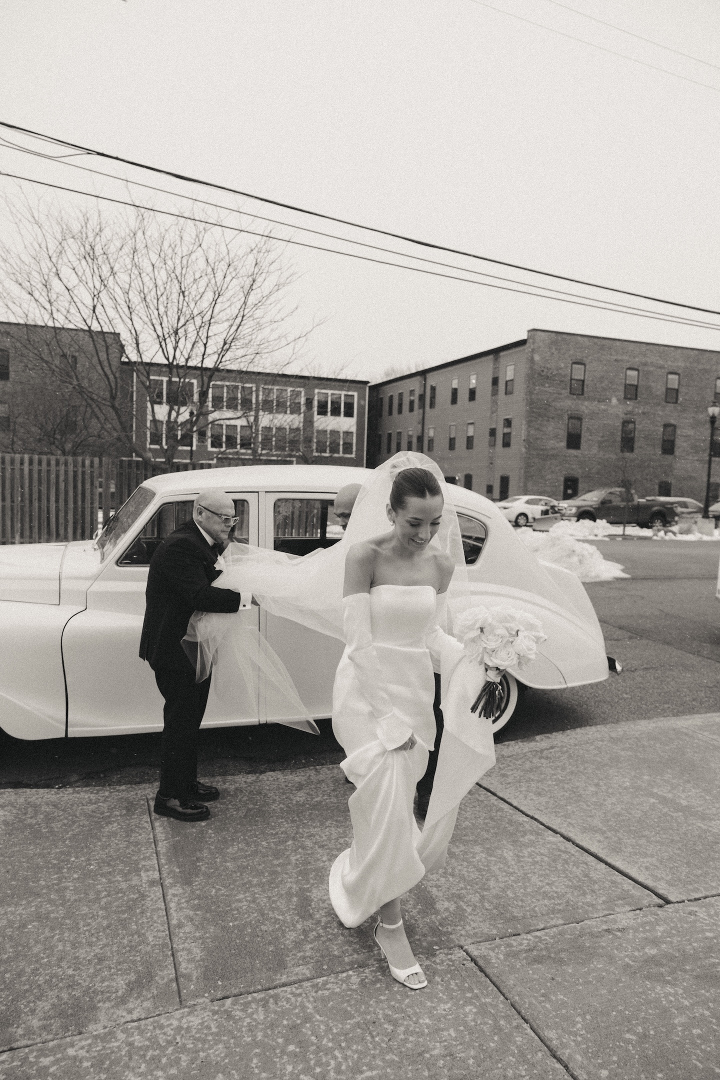 Bride stepping out of a vintage car with her bouquet, a candid moment worth adding to any wedding shot list